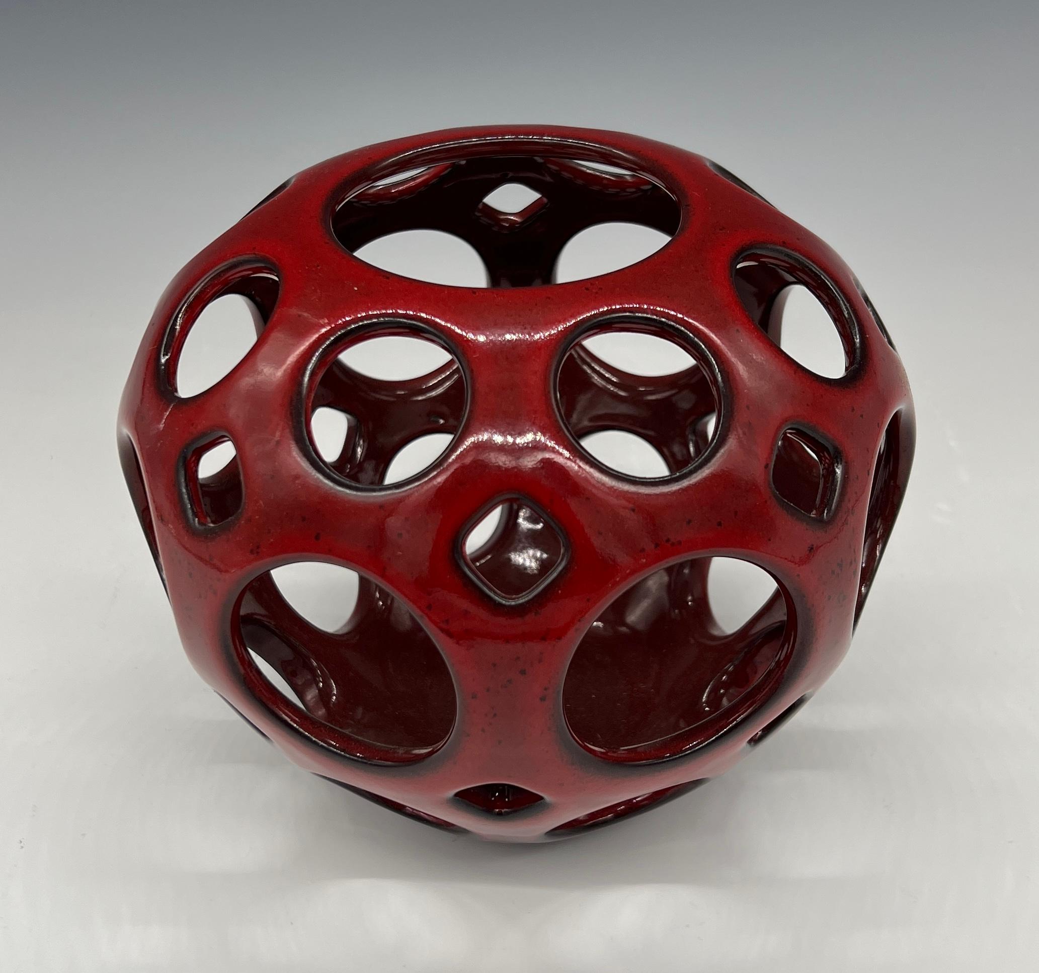 This wheel thrown, hand pierced ceramic tabletop sculpture/ vessel. with its vibrant red glaze that breaks to black, this piece provides the perfect pop of color to any room. It can stand alone as an art piece, or with a candle, it can illuminate a