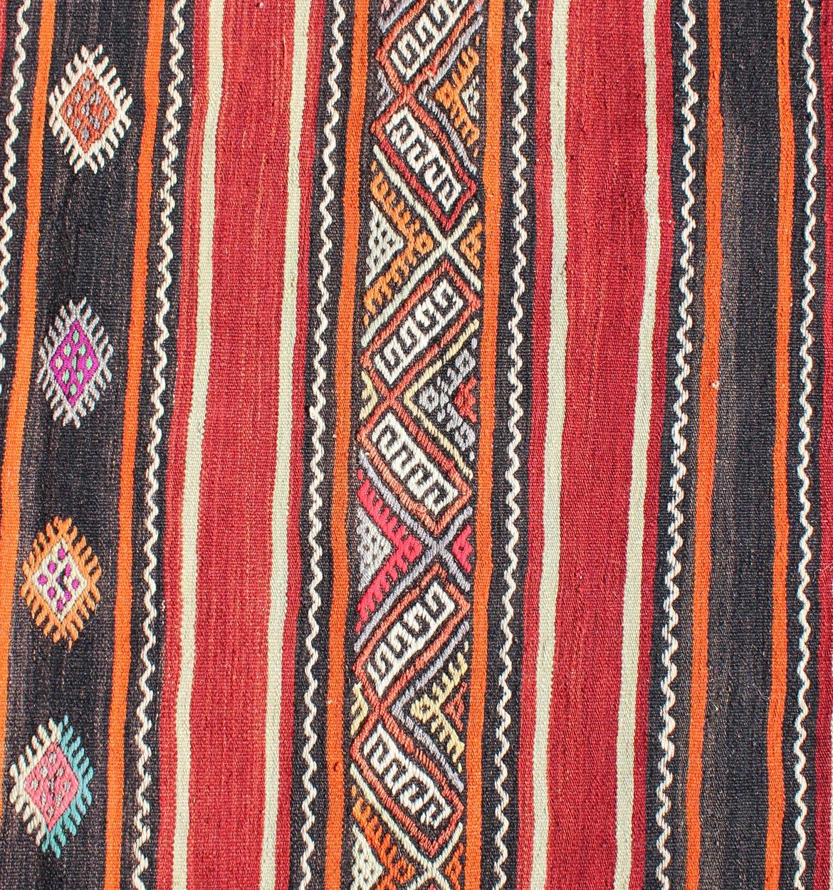 Ein wunderschöner kleiner Stammes-Kilim in Rot, Schwarz und mehreren Farben. Dieses Vintage-Flachgewebe ist zum Teil mit Stickereien verziert.
Maße: 4'2 x 6'