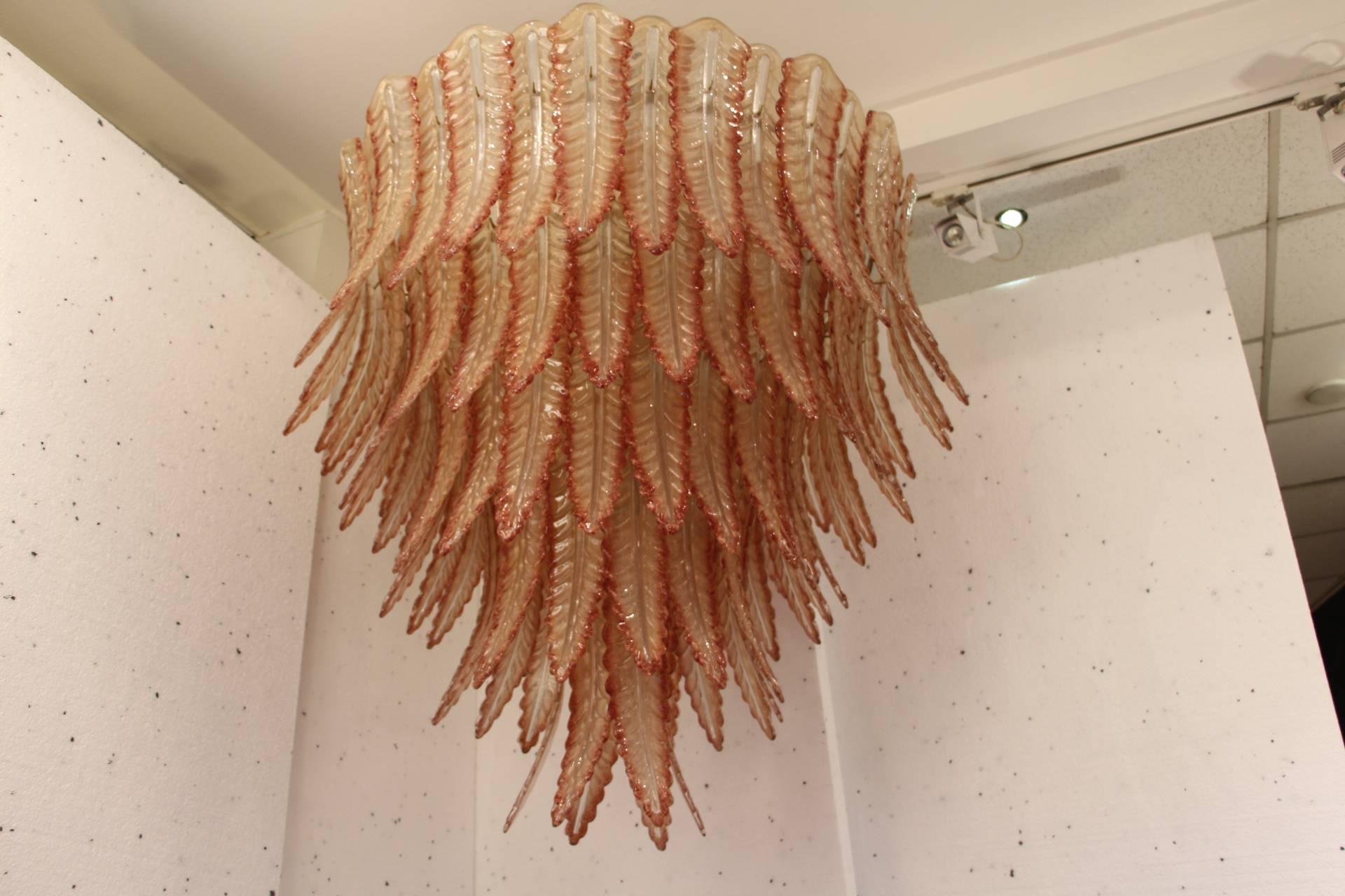This spectacular chandelier features beautiful Murano glass palmettes in champagne beige color with red hedges. The mix of these two colors results in a kind of very warm pink general color.
It gives a warm and pleasant light and provides a