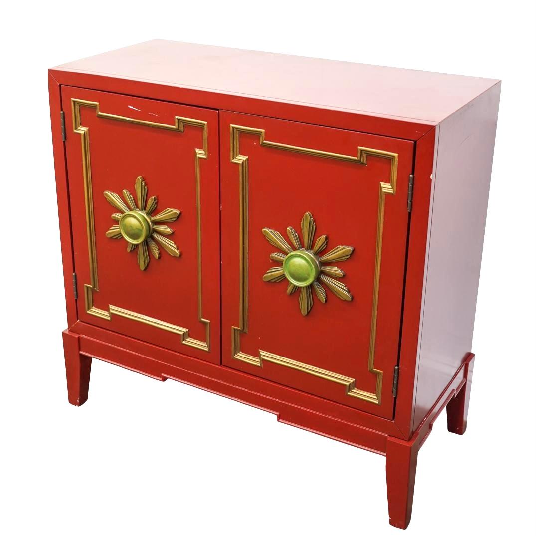 Vintage style red and gold carved wood cabinet is a striking example of craftmanship, combining rich color with intricate detailing. Cabinet features double hinged doors, each adorned with over-sized starburst shaped pulls, and gold cabinet molding,