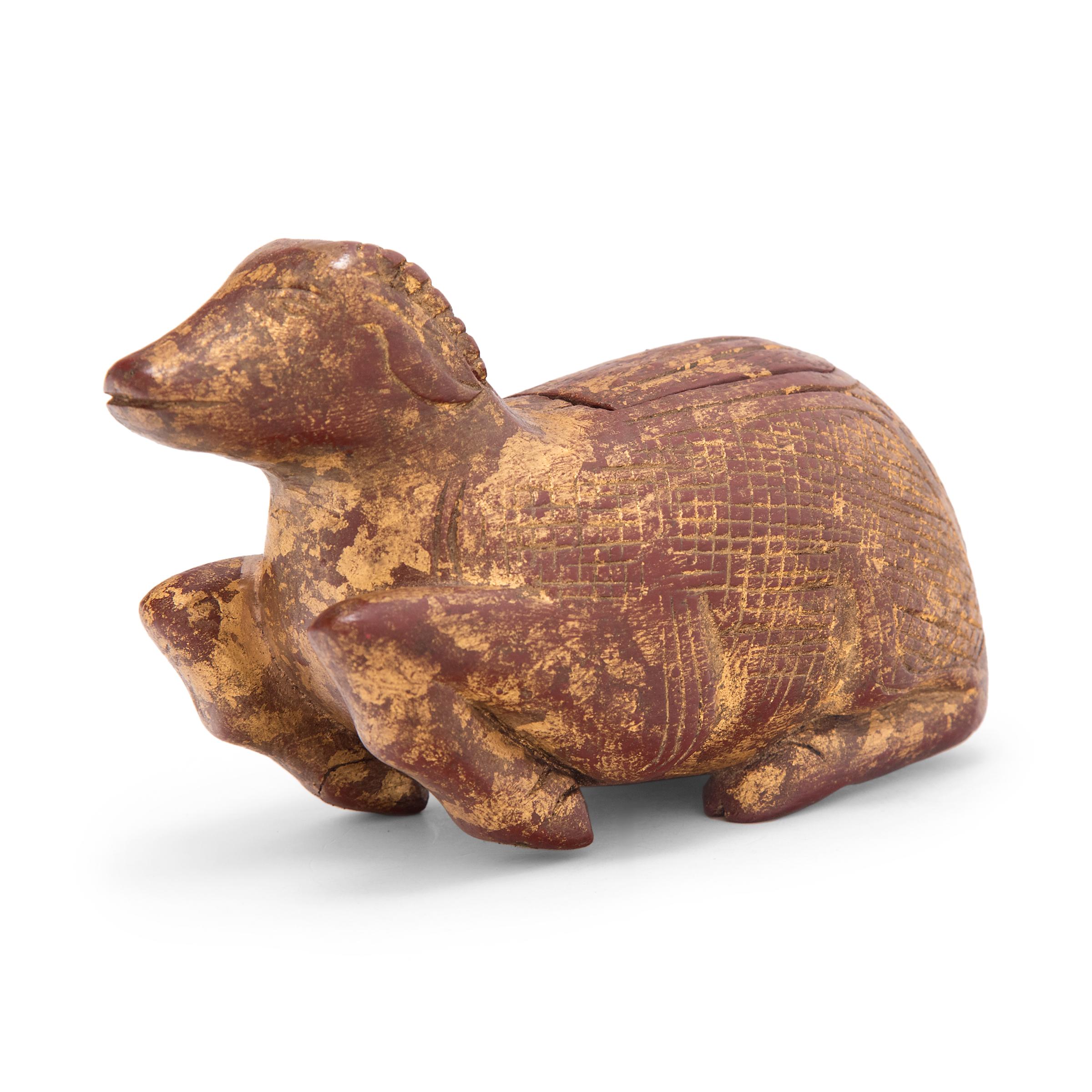 This petite gilt box is hand-carved in the form of a reclining ram or goat, a Buddhist symbol of immortality, power, determination. The ram has a relaxed posture, his feet tucked beneath his stomach and a calm expression on his face. The carved