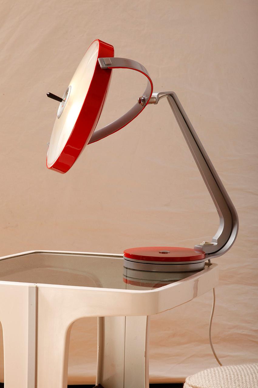 The lamp is made of a combination of aluminum and steel, painted gray and red. It has a rotating base and a lampshade with a diffuser (diffuser) rotated in two planes.

Produced in the late 1960s. Mounted on a 360-degree rotating pedestal. The