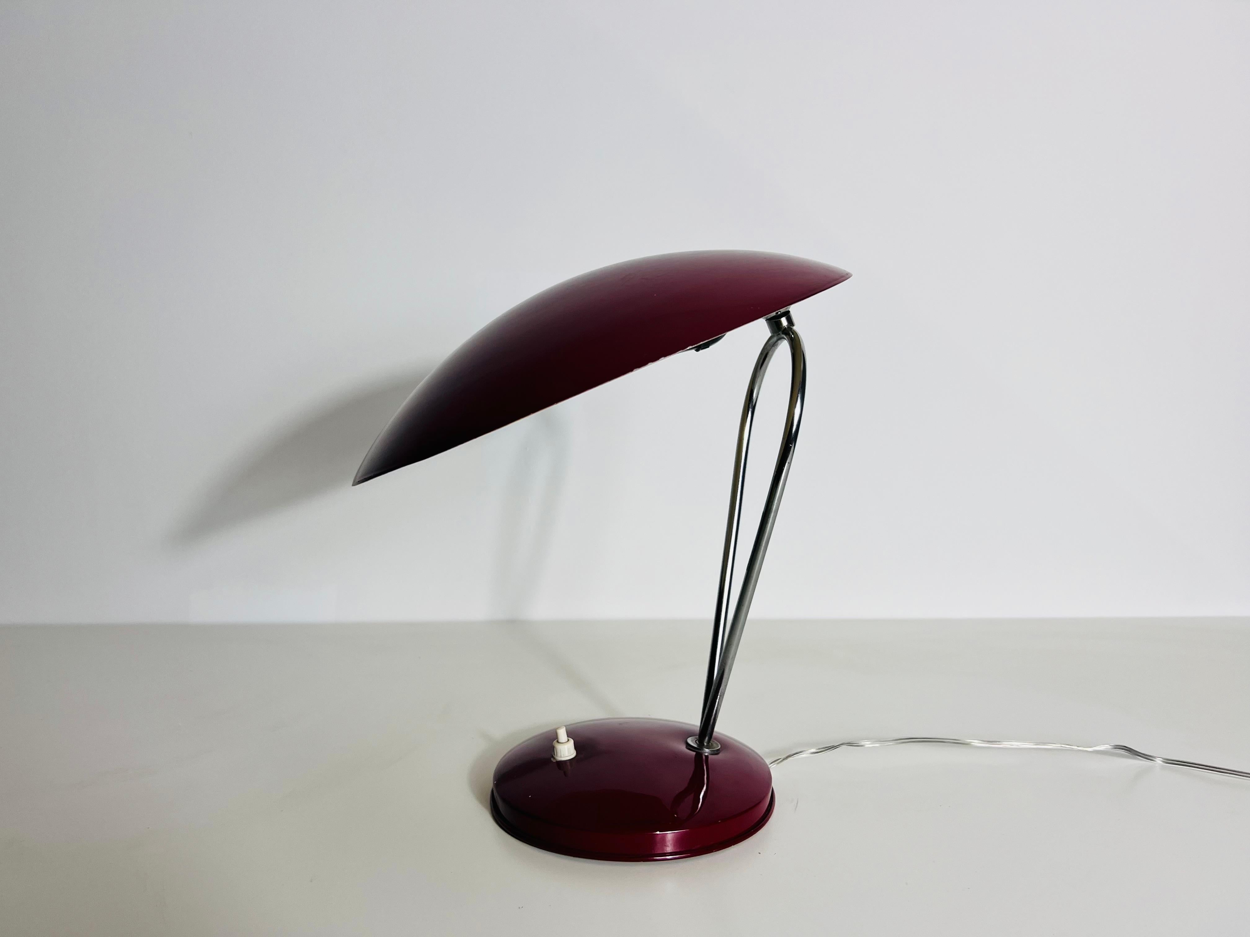 This vintage table lamp, crafted in Italy during the 1960s, is a stunning example of Bauhaus-inspired design. Featuring a sleek chrome double rod and red metal base, this lamp combines functionality with timeless style. The unique red metal