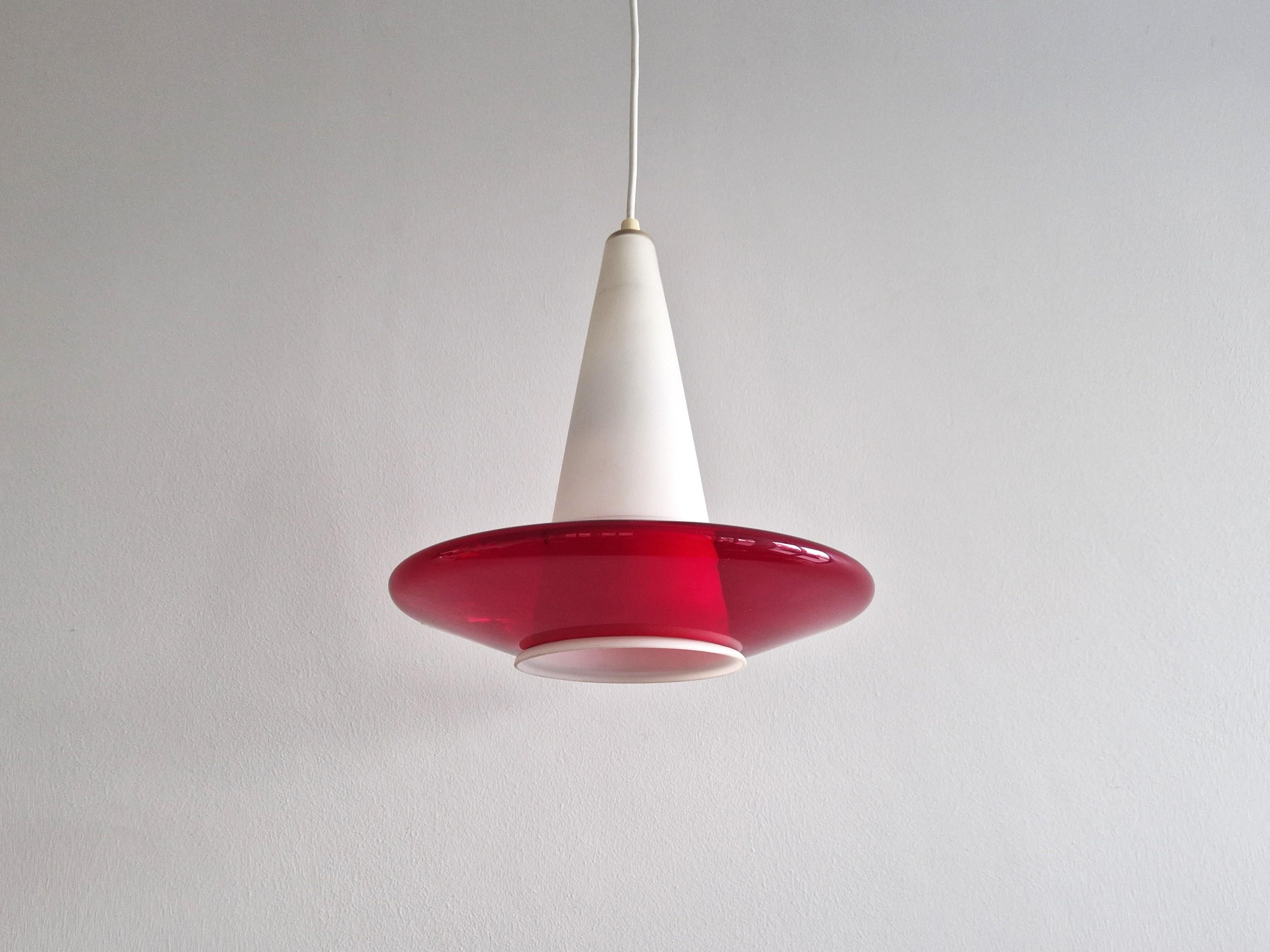 This stunning pendant lamp is made out of white opaline glass surrounded with a clear red glass UFO shaped shade. In the style of Louis Kalff for Philips or Peil und Putzler with resemblance also to designs of Nordisk Solar. We haven't seen this