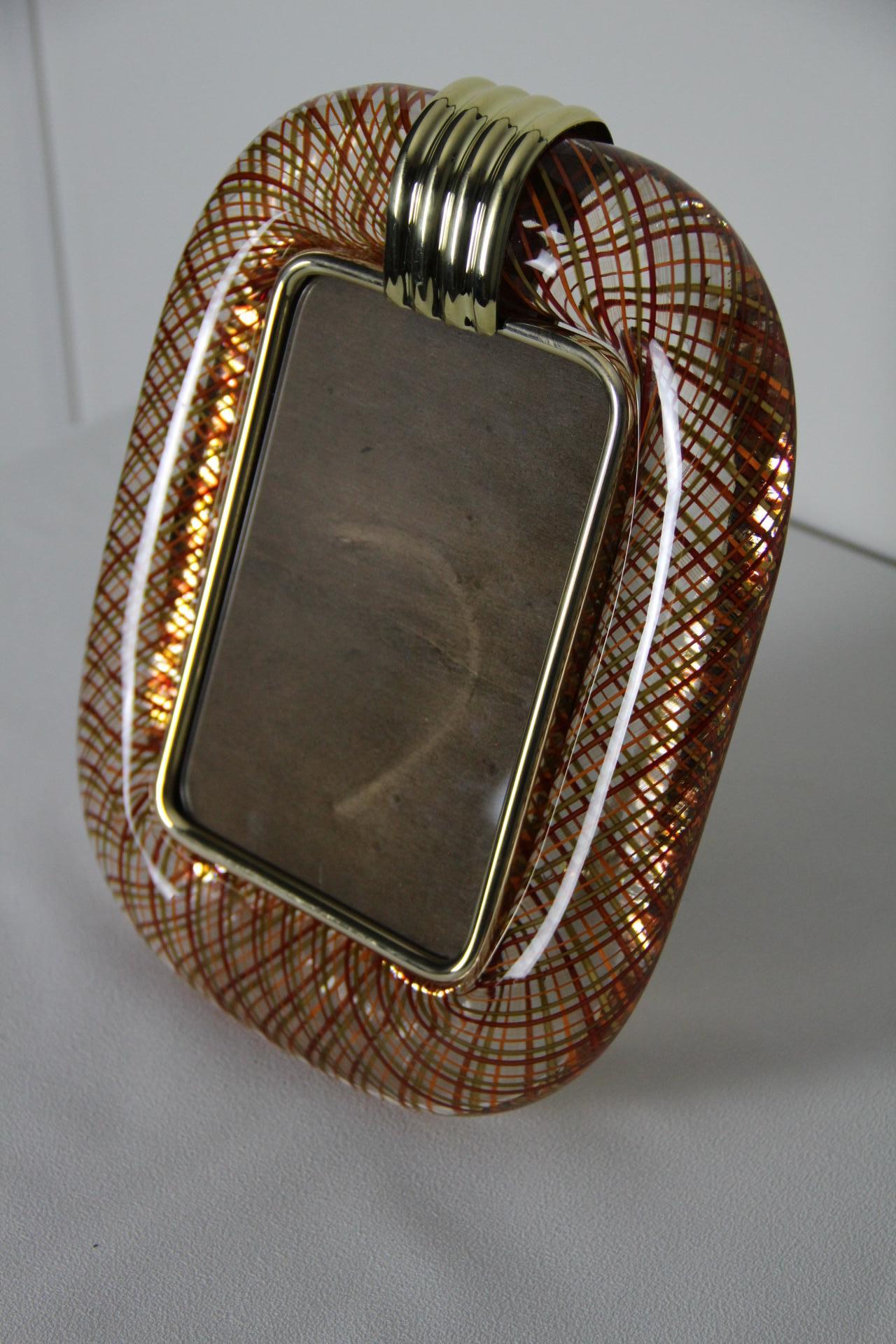 Ce magnifique cadre photo vertical est purement dans la fabrication du verre vénitien  tradition. La technique utilisée pour obtenir ce riche effet optique est appelée filigrana et nécessite des artisans hautement qualifiés. 
Ce cadre photo est