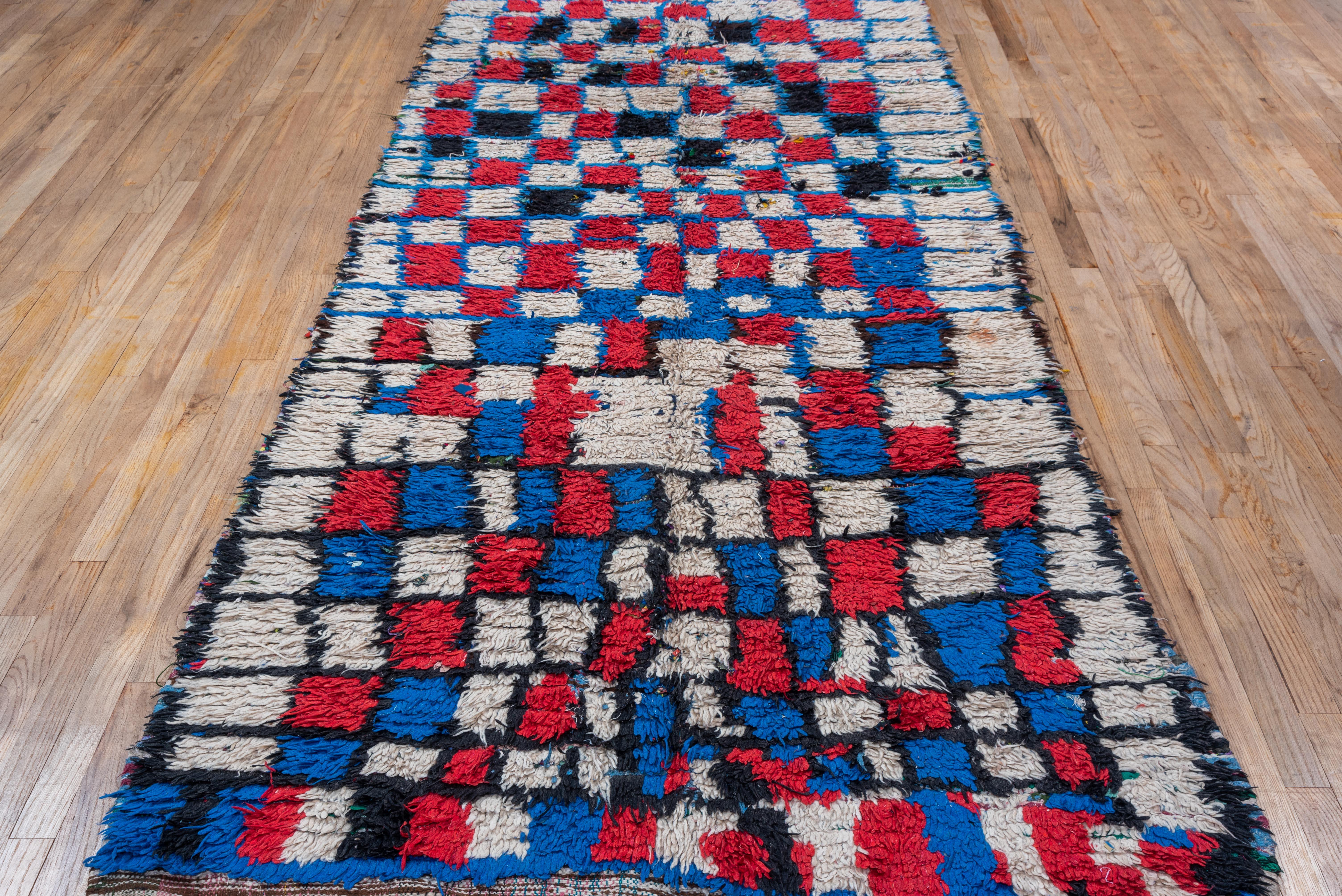 This hand-knotted village rug features a box pattern throughout, shaped with blue threads to create cream and red colored boxes all over. 