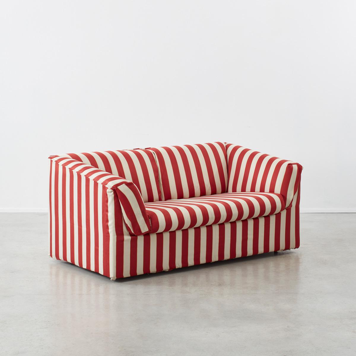 A cosy two-seater mid-century sofa with gently sloping armrests. Upholstered in a bold red and white striped fabric. This sofa is very comfortable to sit in and makes a strong visual statement.