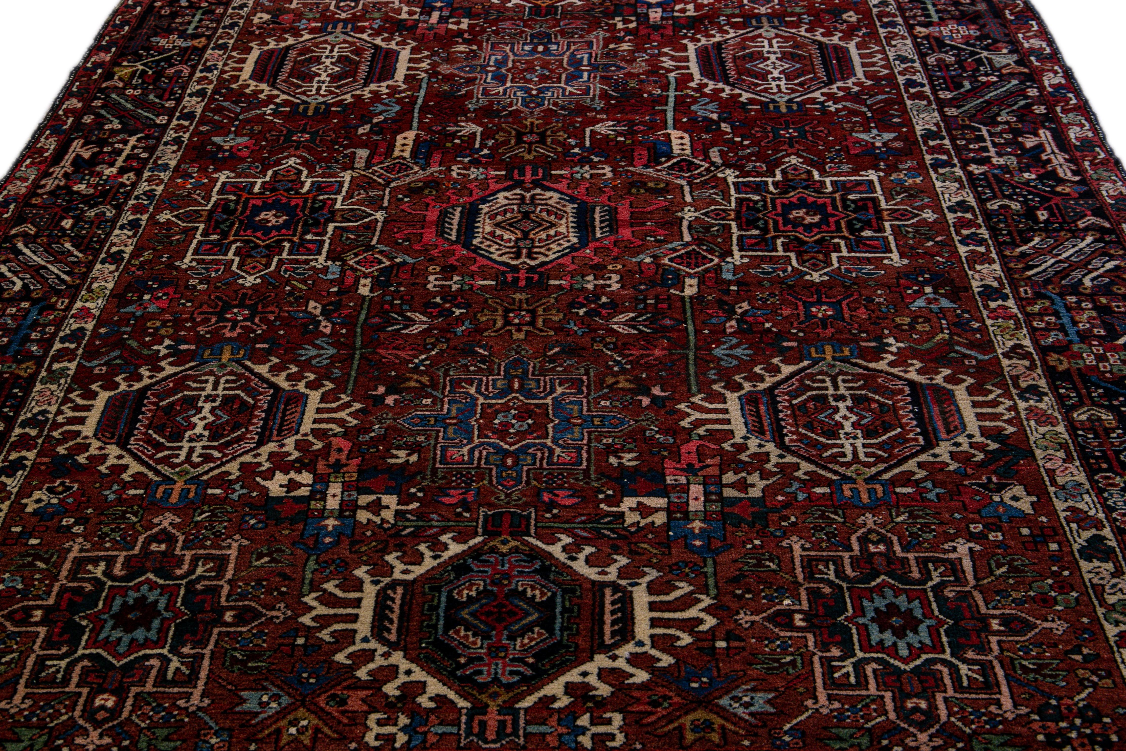 Beautiful antique Heriz hand-knotted wool rug with a rust field. This rug has a blue frame and multicolor accents in a gorgeous all-over geometric medallion floral design.

This rug measures 6' 2