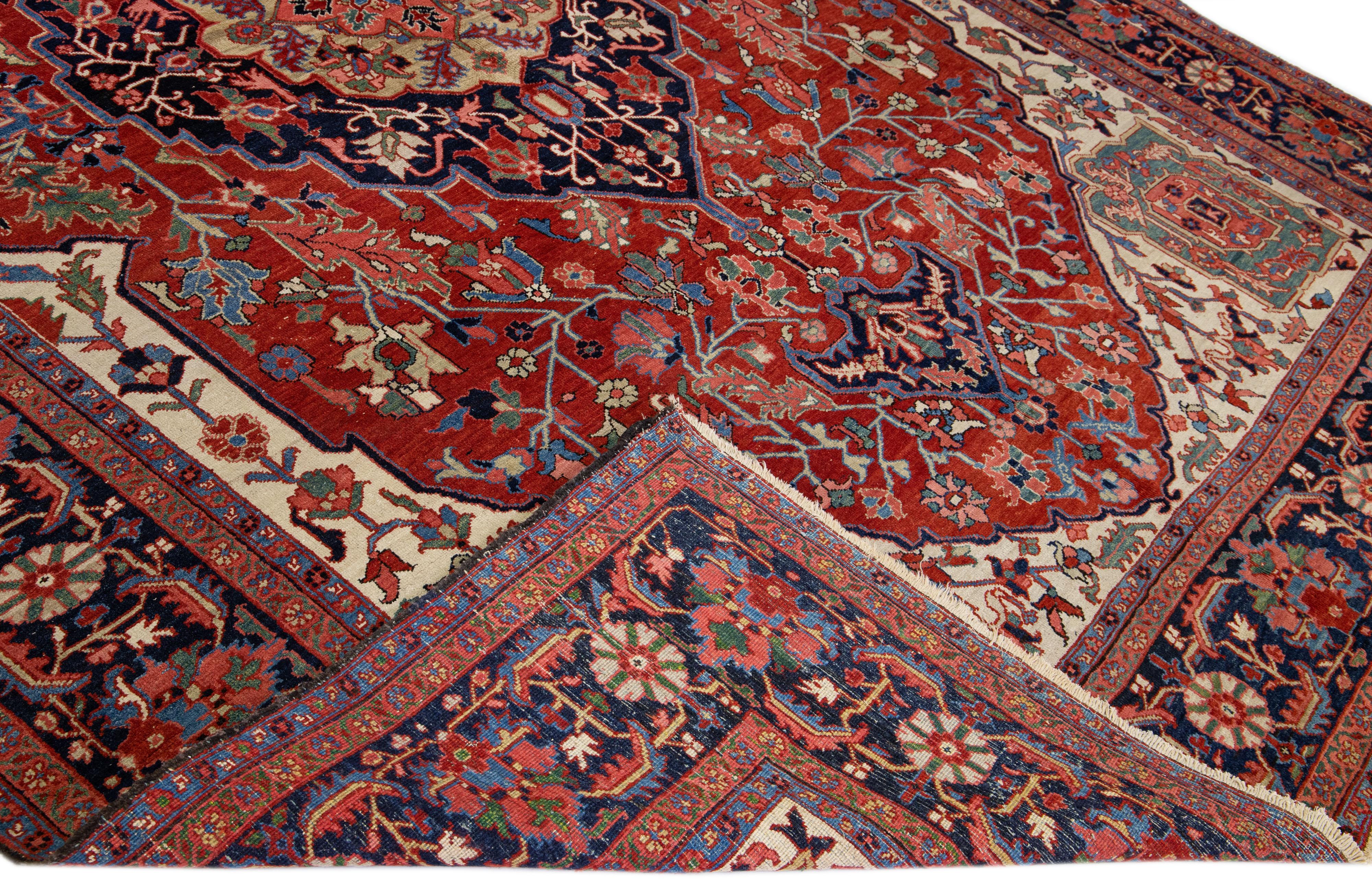 Schöner antiker persischer Heriz-Handknüpfteppich aus Wolle mit rotem Feld. Dieser Heriz-Teppich hat einen marineblauen Rahmen und mehrfarbige Akzente in einem prächtigen geometrischen Medaillon-Blumenmuster.

Dieser Teppich misst: 9'9