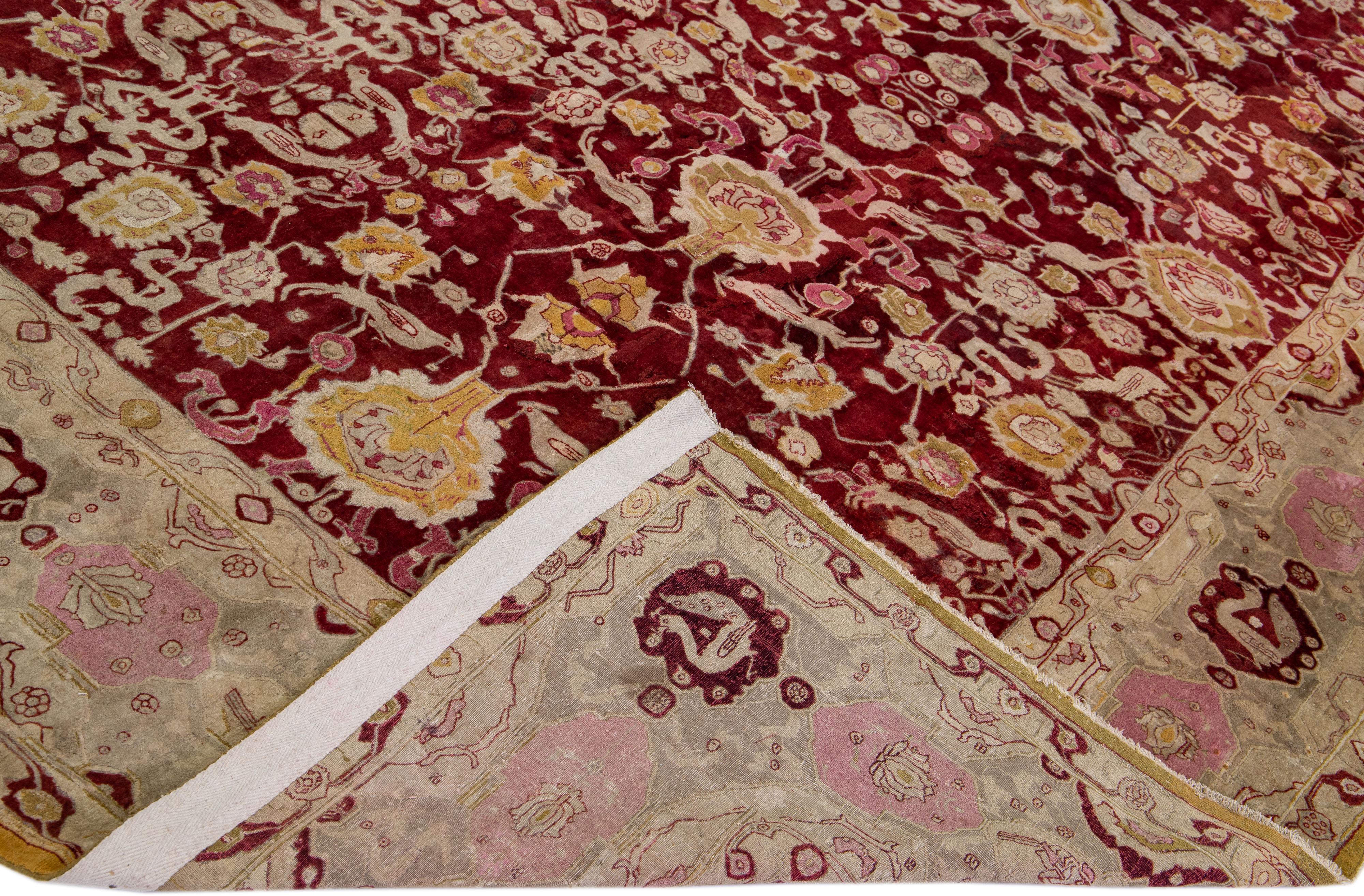 Beautiful antique Agra hand-knotted wool rug with a red field. This Indian rug has beige, pink, and goldenrod accents in a gorgeous all-over floral pattern design.

This rug measures: 11'10