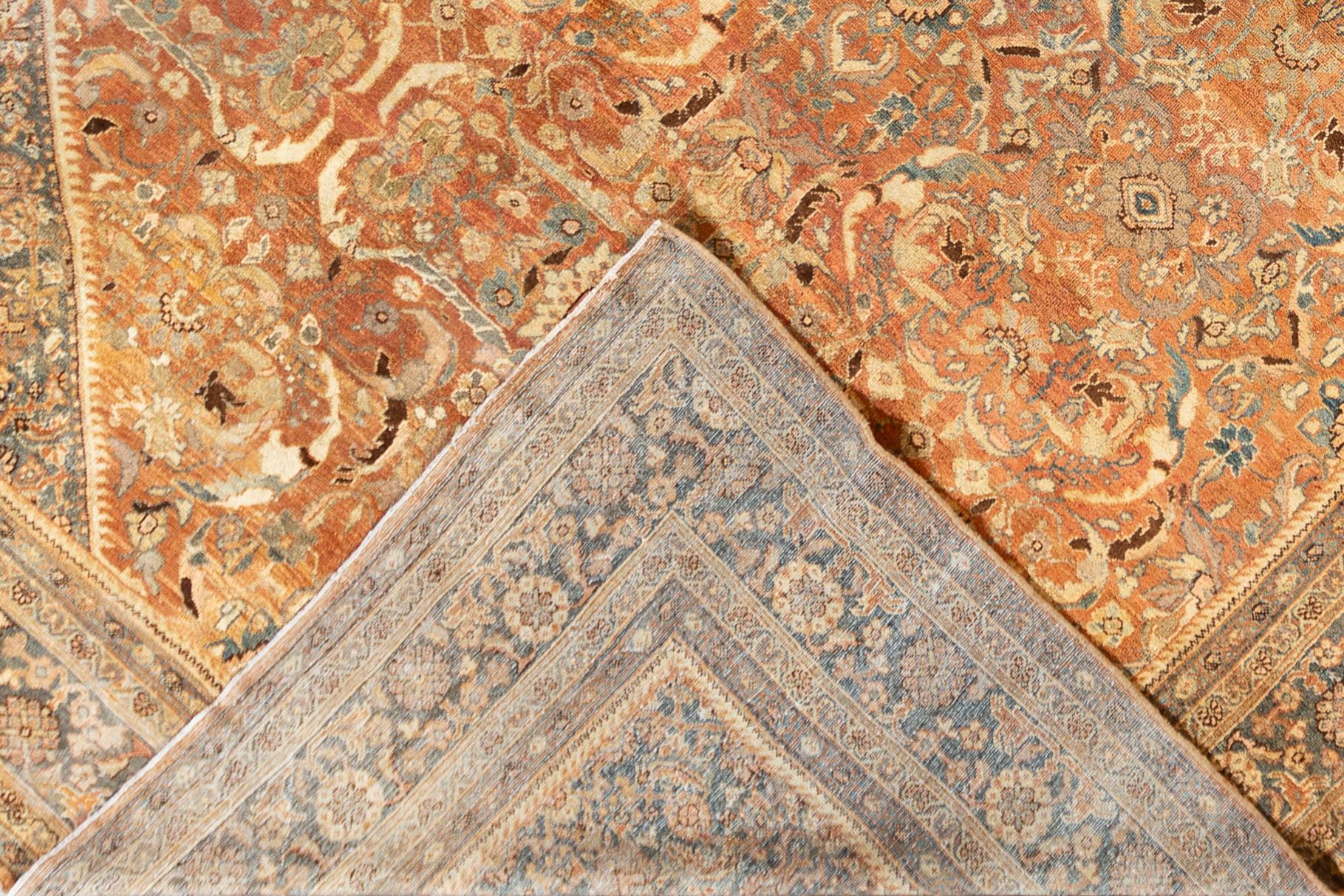 Magnifique tapis persan antique Mahal en laine nouée à la main avec un champ rouillé. Cette pièce a un cadre bleu et des accents multicolores dans un magnifique motif floral géométrique.

Ce tapis mesure : 11'3
