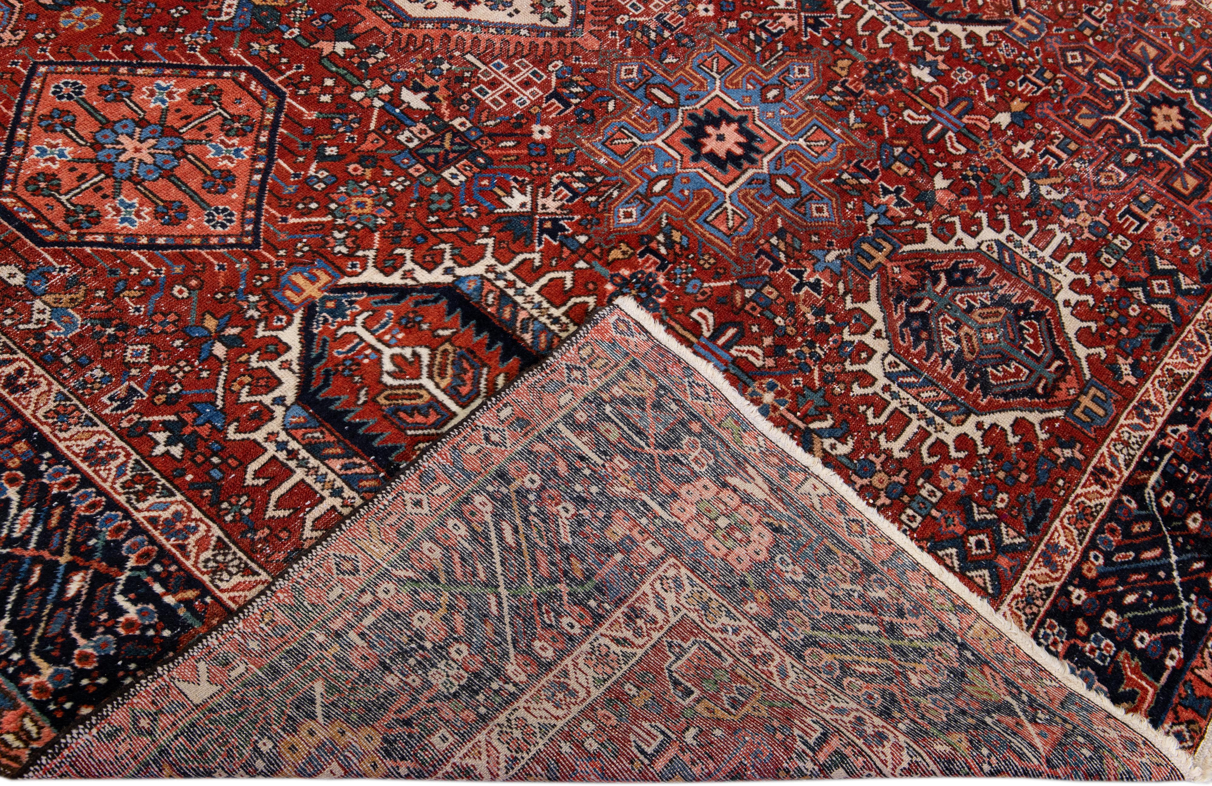 Beautiful antique Heriz Serapi hand-knotted wool rug with a red field. This Heriz rug has a navy-blue designed frame and multi-color accents in a gorgeous all-over geometric design.

This rug measures: 7'7
