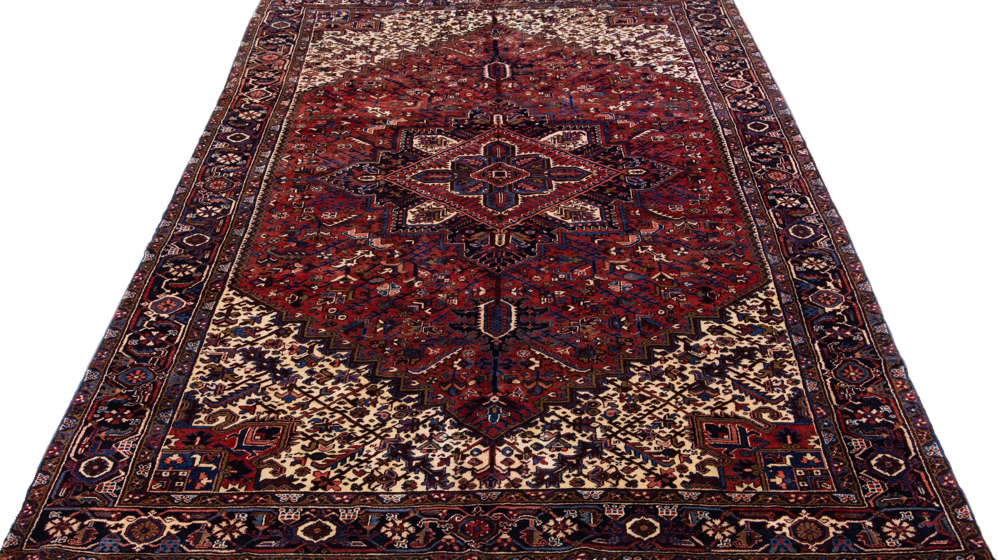 Beautiful antique Heriz hand-knotted wool rug with a red color field. This Persian rug has a navy blue frame and multicolor accents in a gorgeous all-over medallion floral design.

This rug measures: 8'9