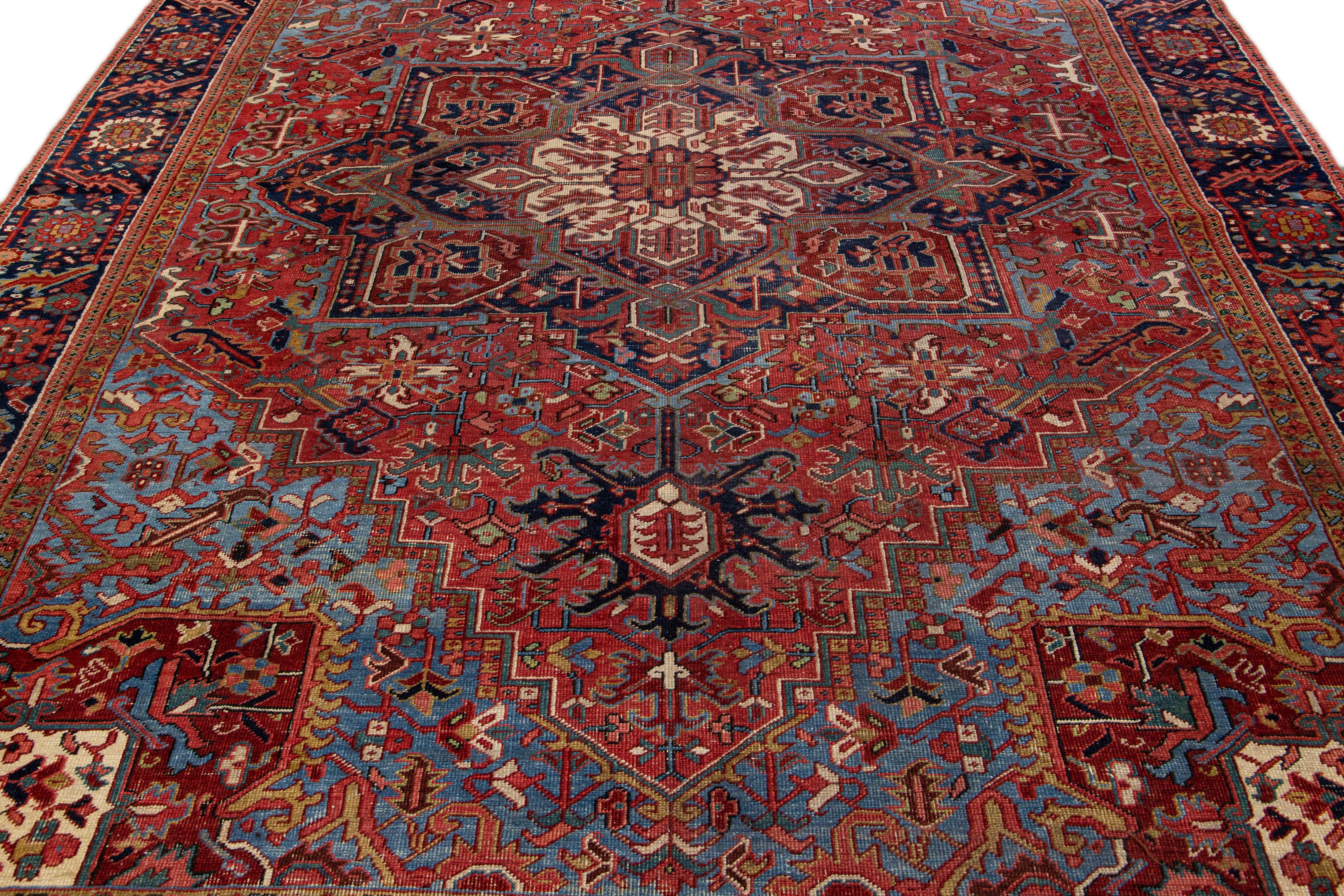 Beautiful antique Heriz hand-knotted wool rug with a red field. This Heriz rug has a navy-blue frame and multi-color accents in a gorgeous all-over Medallion floral design.

This rug measures: 9'5