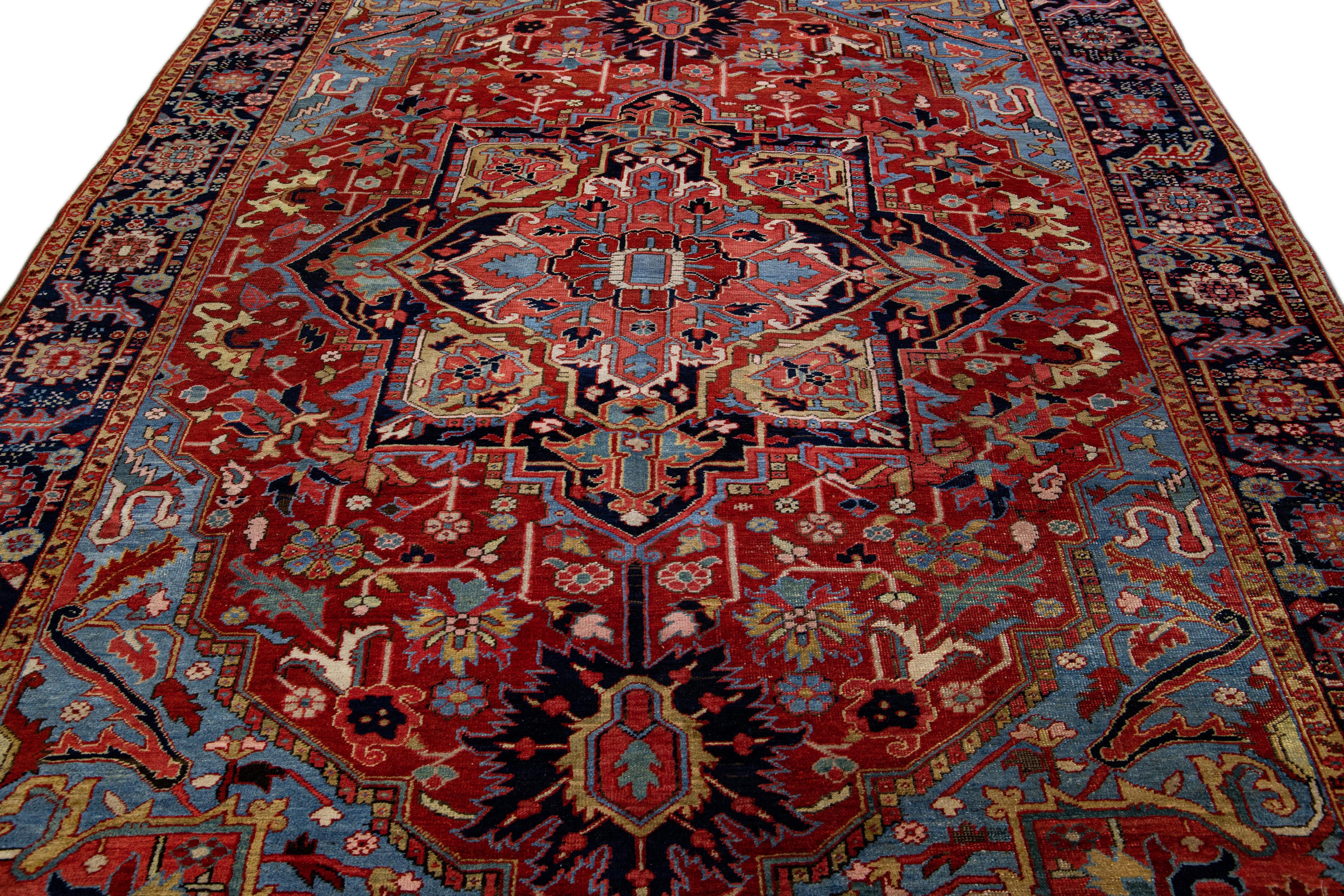 Preciosa alfombra antigua Heriz de lana anudada a mano con campo rojo. Esta alfombra Heriz tiene un marco azul marino y detalles multicolores en un precioso diseño floral Medallón.

Esta alfombra mide 7'8