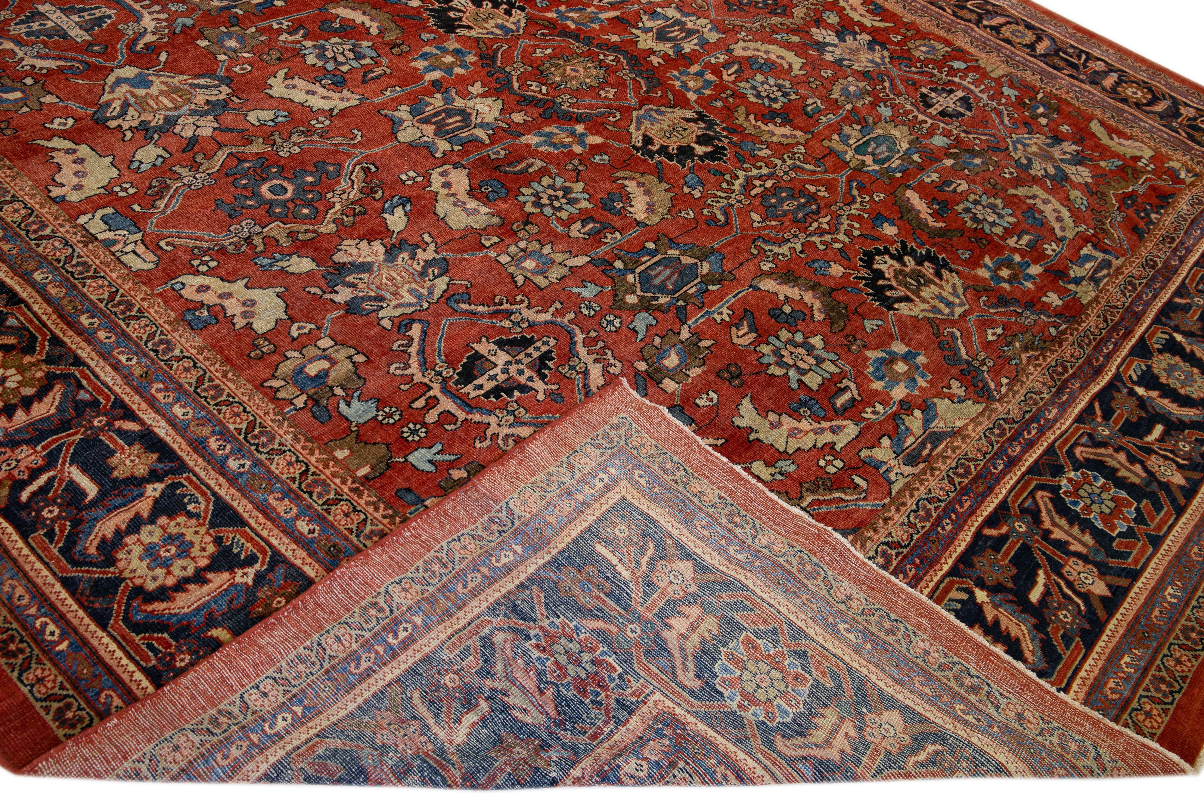 A beautiful Antique Mahal hand-knotted wool rug with a red color field. This rug has a navy blue frame and multicolor accents in an all-over Herati design.

This rug measures 13'5
