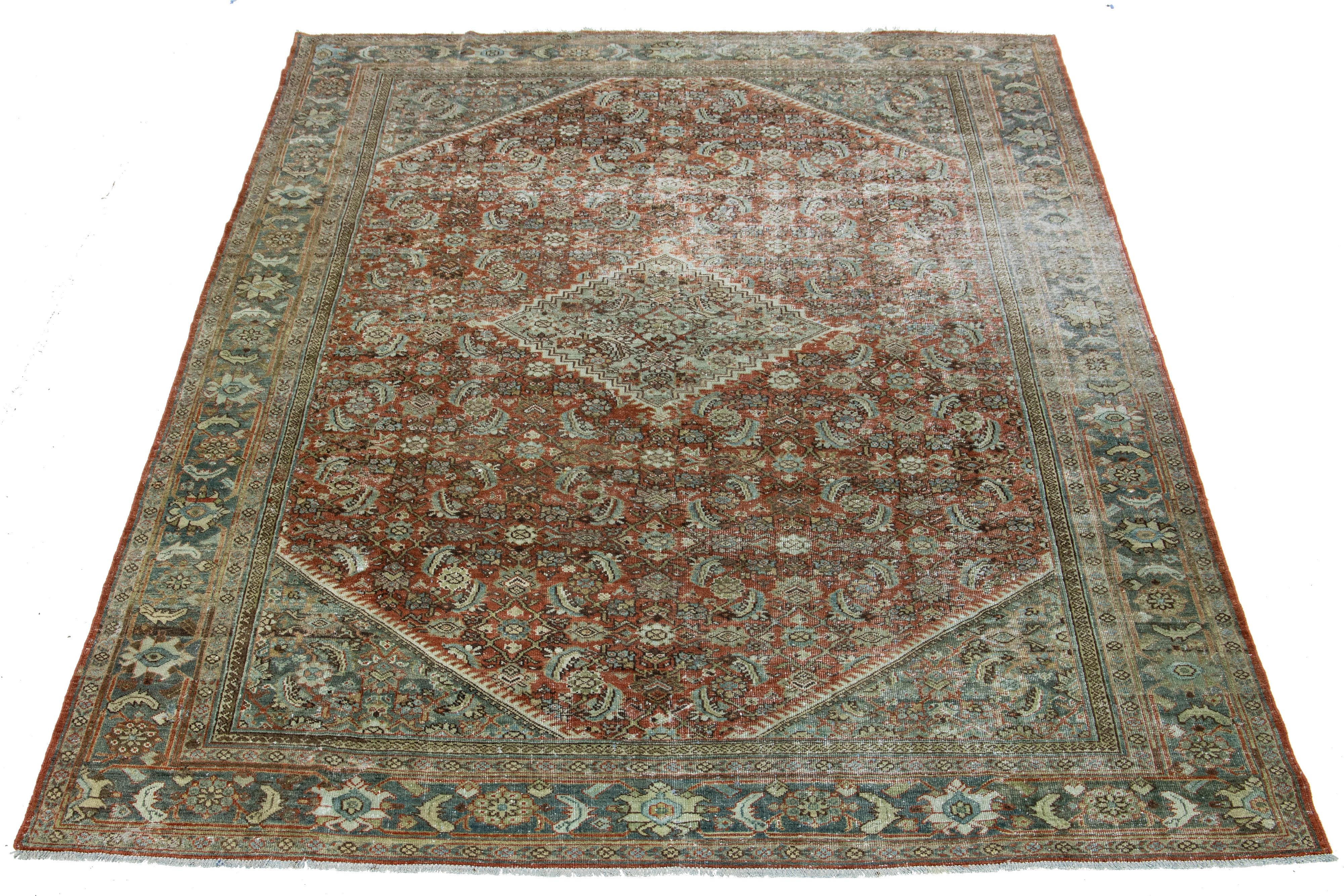 A hand-knotted wool antique Mahal rug features an all-over design with blue, brown, and beige accents on a red rust color field.

This rug measures 8'6