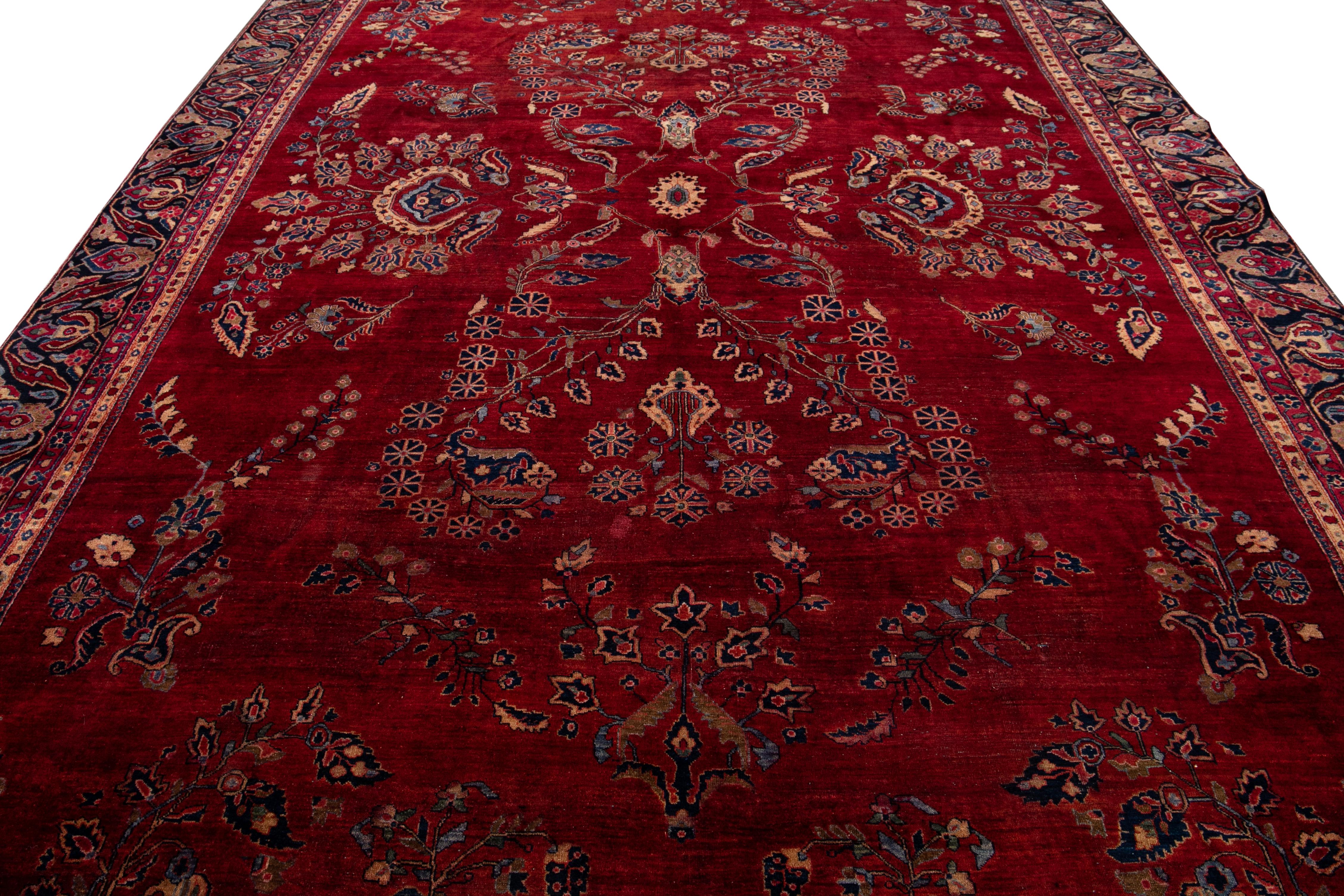Dieser opulente antike Teppich aus dem persischen Sarouk ist von Hand gefertigt und besteht aus Wolle. Es zeigt ein rotes Feld, das von einem filigranen blauen Rahmen umrahmt wird, der mit bunten Details angereichert ist, die in einem atemberaubend