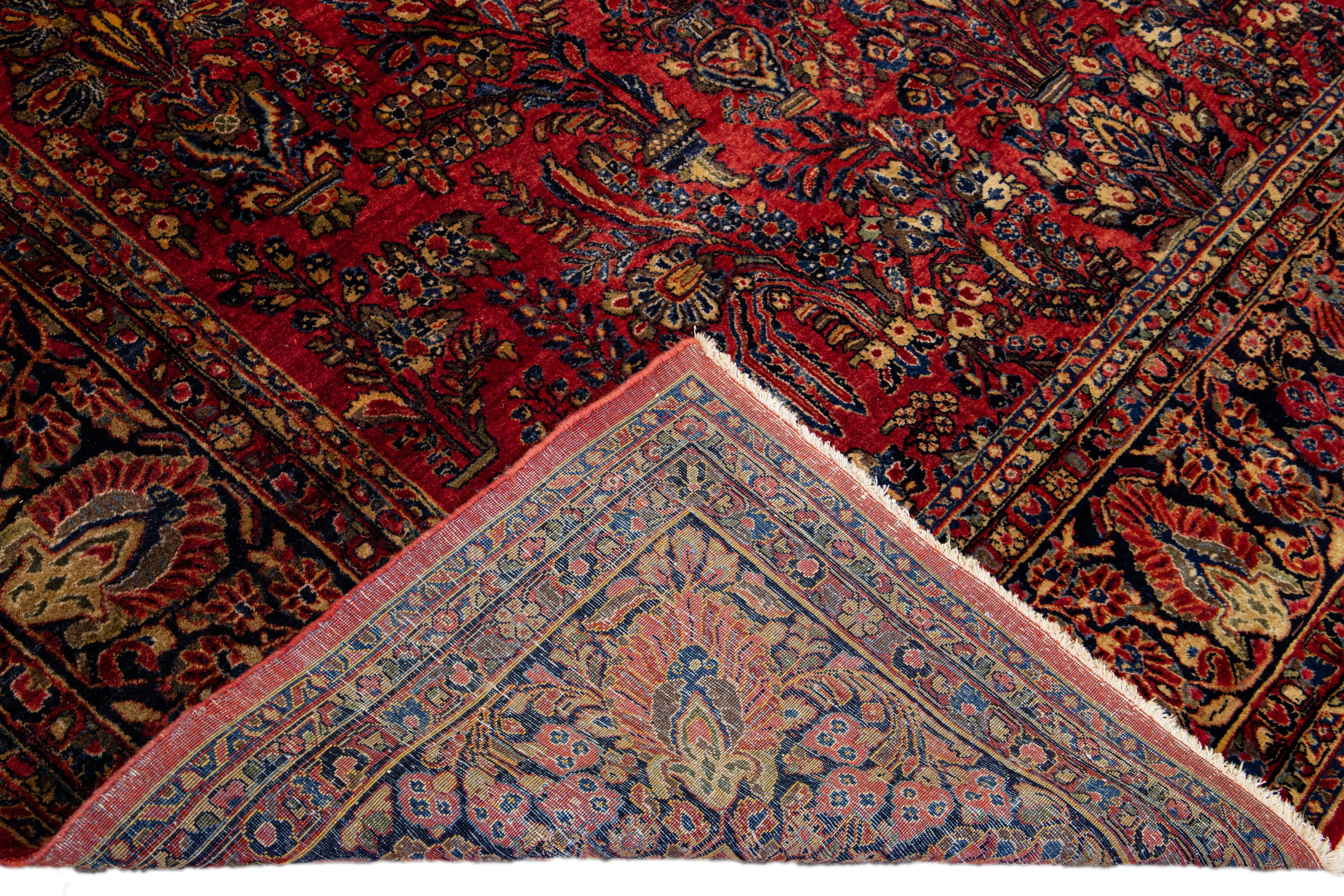 Beautiful antique Sarouk Persian hand-knotted wool rug with a red field. This Persian rug has a designed frame and blue, green, and brown accents in a gorgeous all-over traditional floral design. 

This rug measures: 10'5