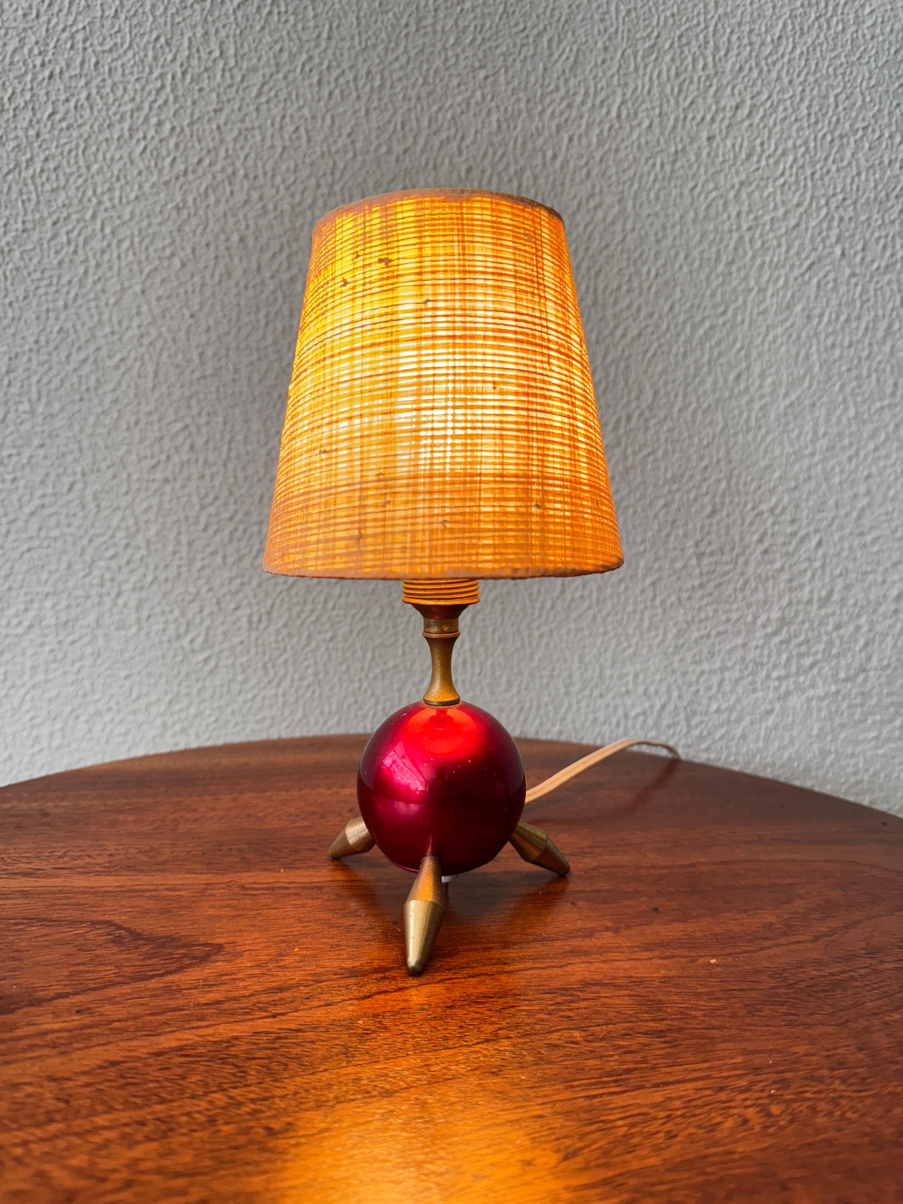 Trouvaille ludique et rare de l'Italie des années 1950, cette lampe de table tripode atomique rouge incarne l'esprit exubérant de l'ère atomique sous une forme miniature. Sa petite taille est précisément ce qui la rend si intrigante - une pièce