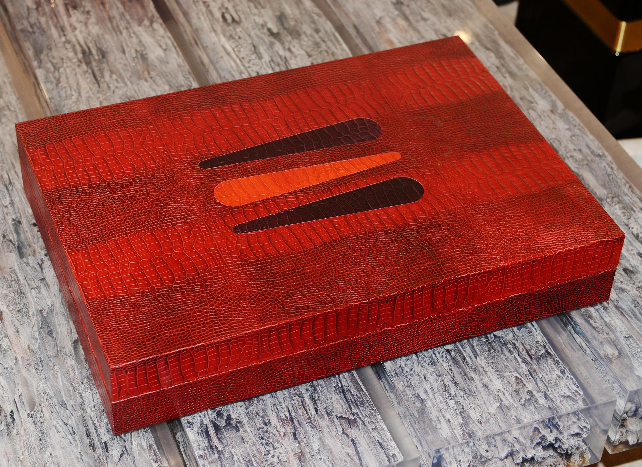 Backgammon Red with structure in solid wood and covered with 
genuine grained leather crocodile printed finish and with details 
in polished stainless steel. Backgammon including 1 doubling dice,
1 board, 2 sets of 15 Red pawns and 15 white pawns, 2