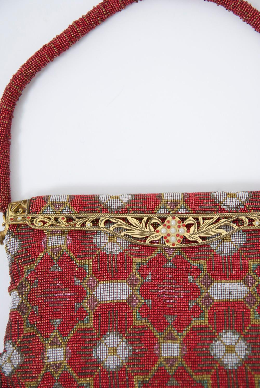 One of the most interesting designs I've seen of the high-style and beautifully crafted French beaded bags from the 1950s-'60s. This example has a red background, white quatrefoil designs and gold design outlines. Goldtone pierced frame, red beaded
