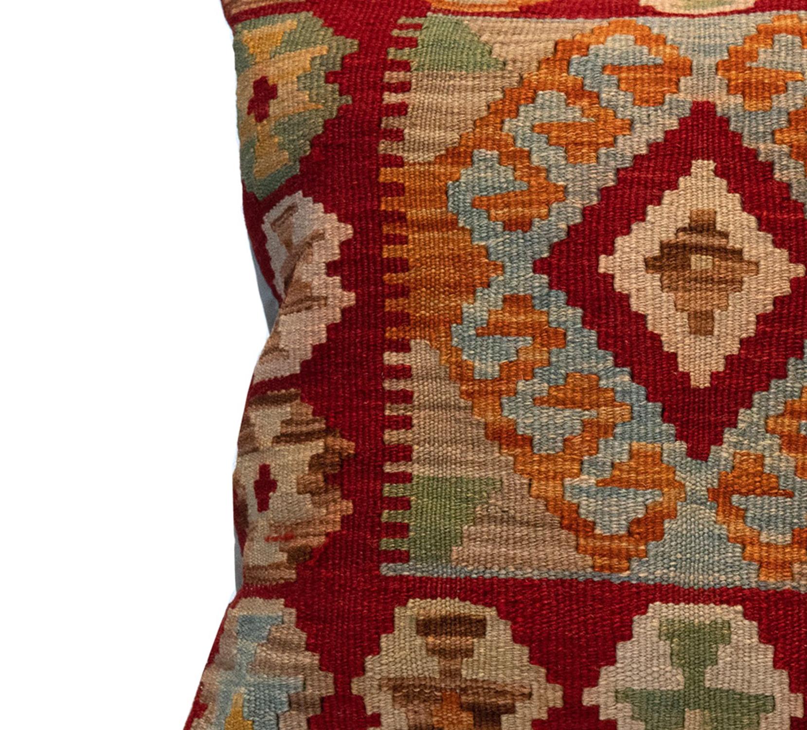 This fantastic cushion has been woven by hand using traditional kilim weaving techniques with hand-spun wool. Featuring a symmetrical geometric pattern woven in beautiful rustic colours. Including rust red, orange, beige and blue. These elegant