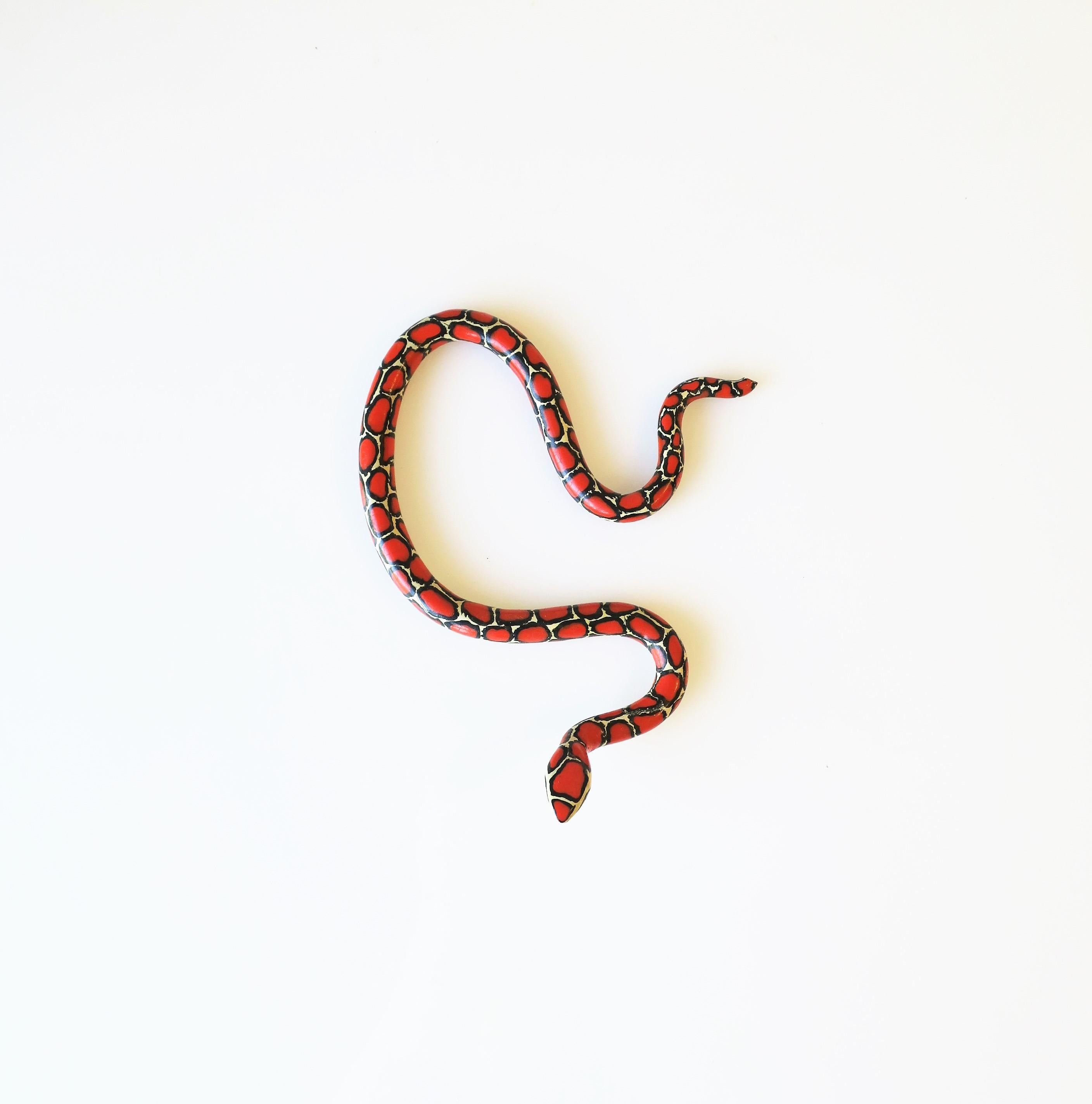 A vintage red, black and white terracotta ceramic snake with green eyes, circa 20th century. Dimensions: 4.25