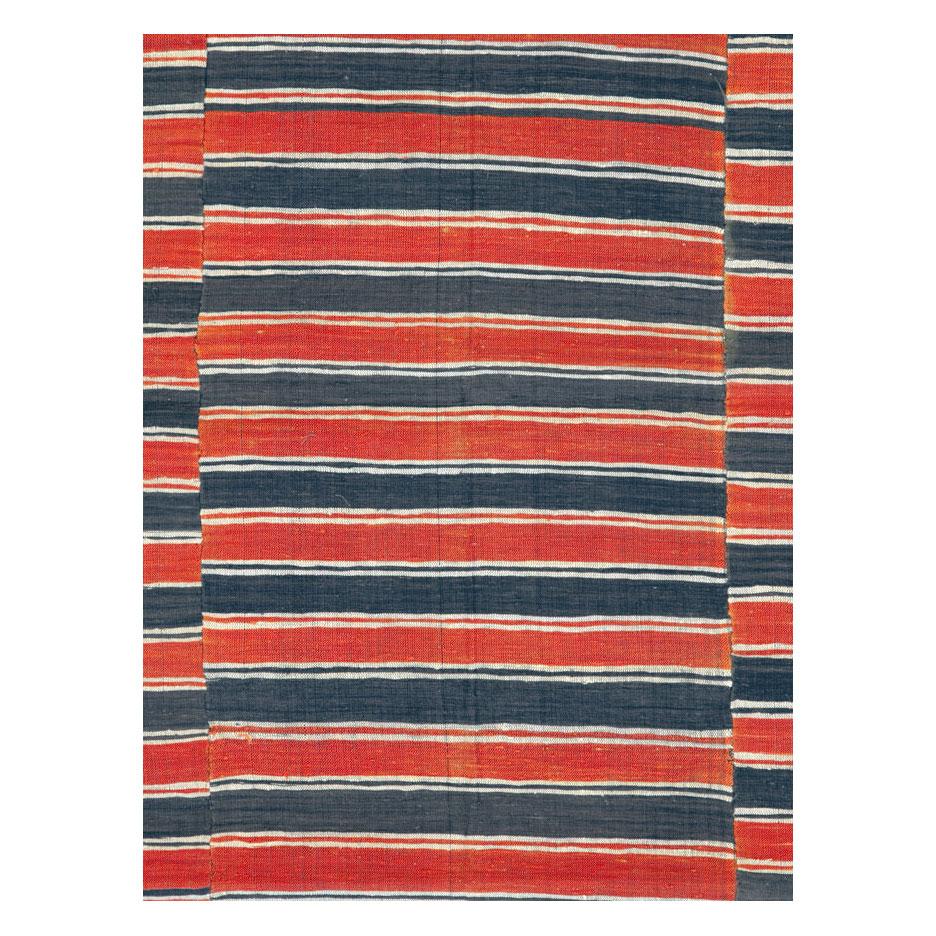 A vintage Turkish flat-weave Kilim accent rug handmade during the mid-20th century with an asymmetrical horizontally striped design in shades of red and black.

Measures: 5' 9