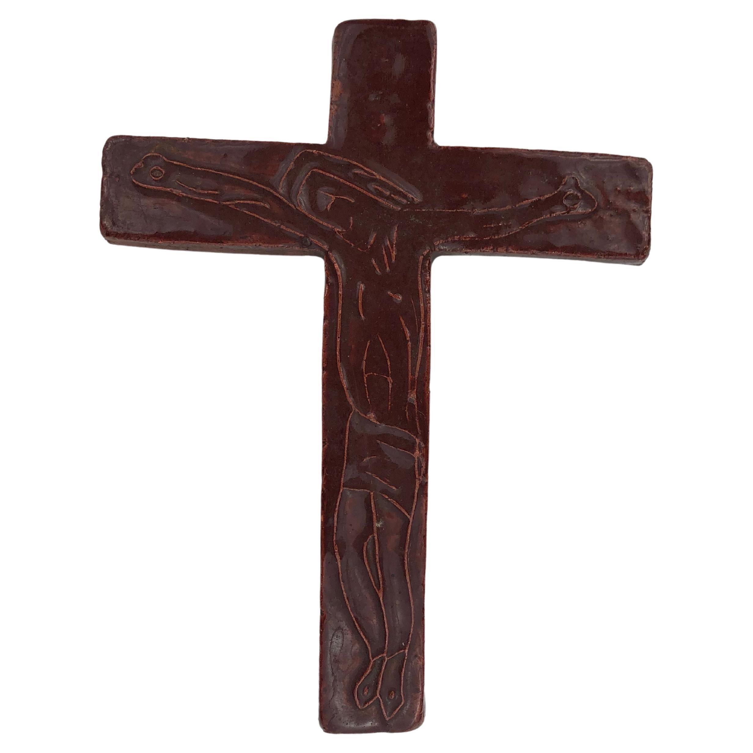 Handcrafted with meticulous attention to detail, this midcentury European ceramic cross has a rich red-brown gloss. At its center an abstract line drawing of a Christ figure is etched in relief. 

The design's core element is the line-drawn Christ