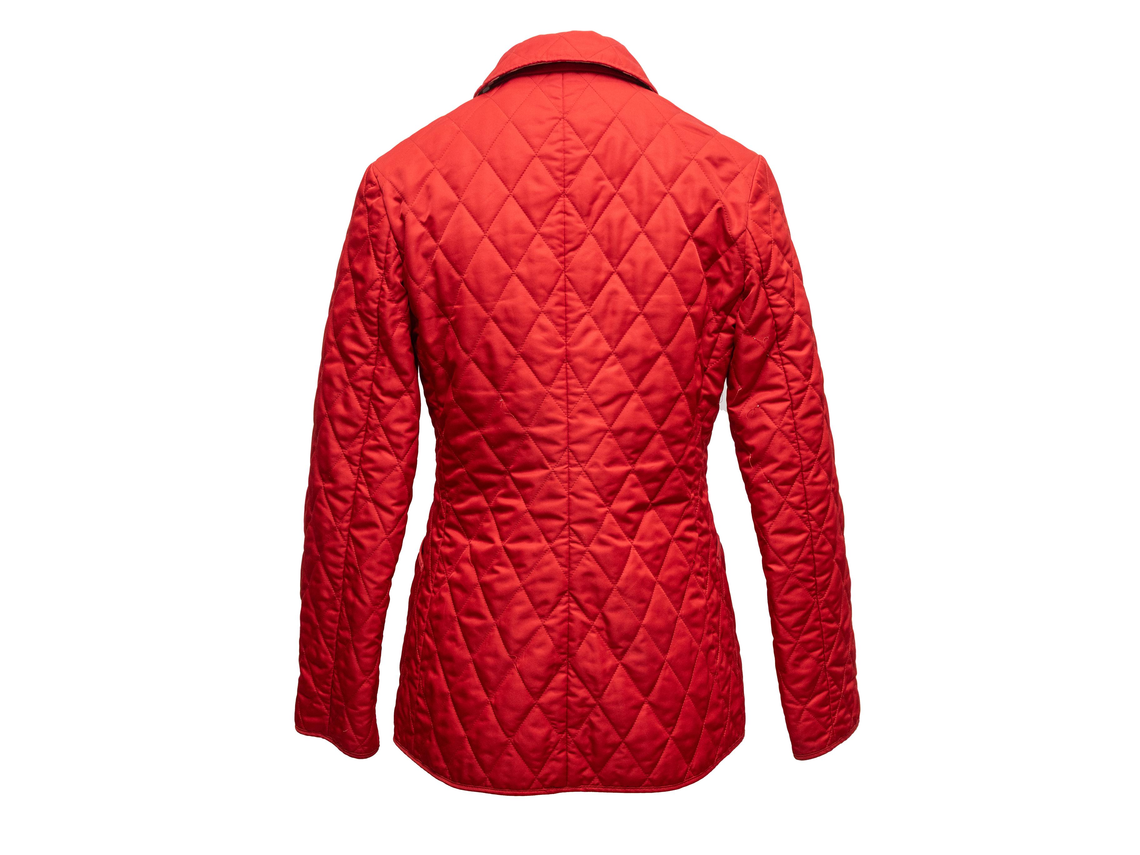 Red quilted jacket by Burberry. Nova Check plaid lining. Dual hip pockets. Front snap closures. 35
