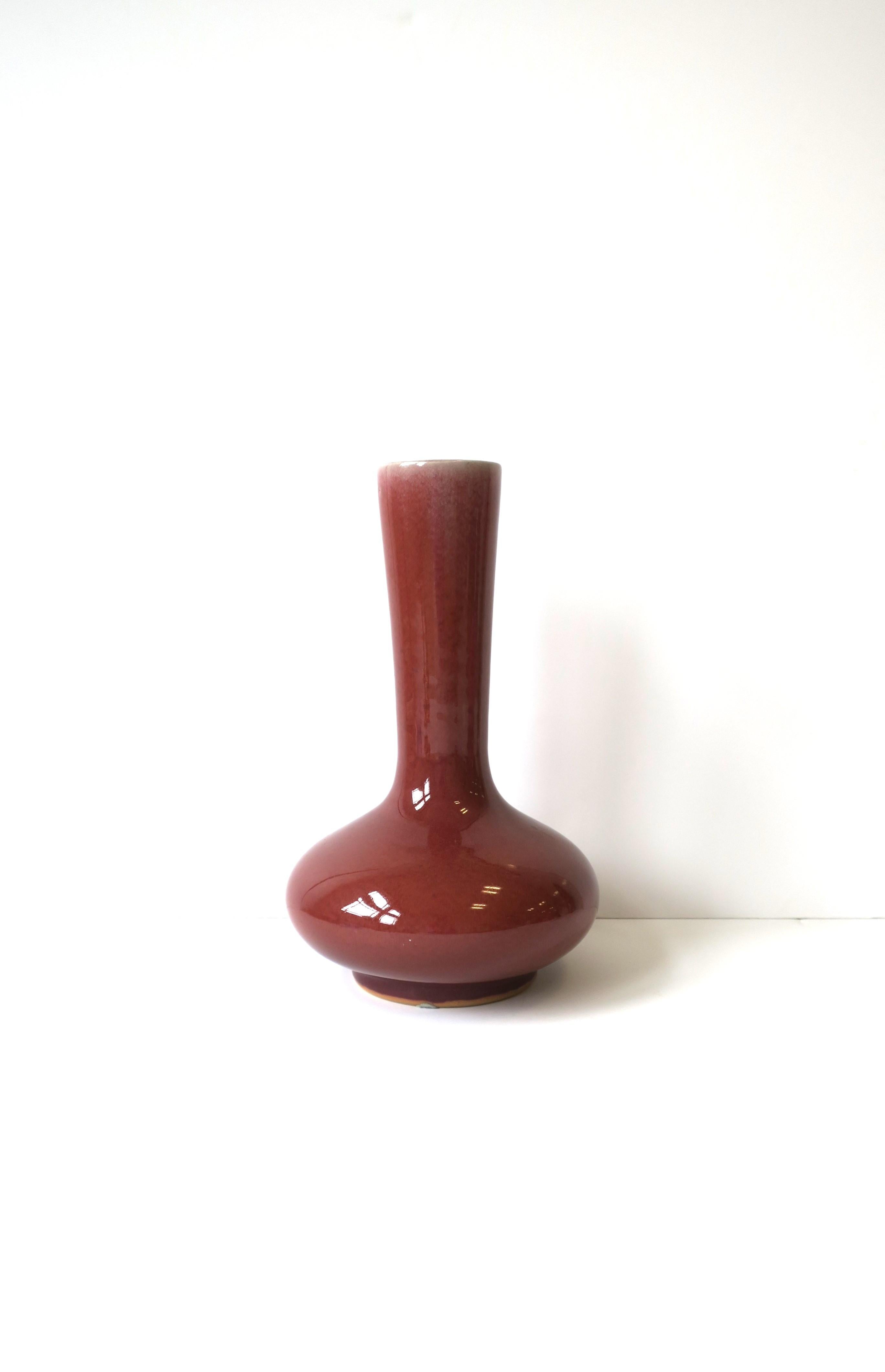 A red burgundy bulbous vase in the Chinese Asian style by designer Maitland-Smith, circa late-20th century, 1990s. Vase is hand-made ceramic pottery in a red burgundy hue with variegated design at top neck area. Piece has potters' stamp and markers'
