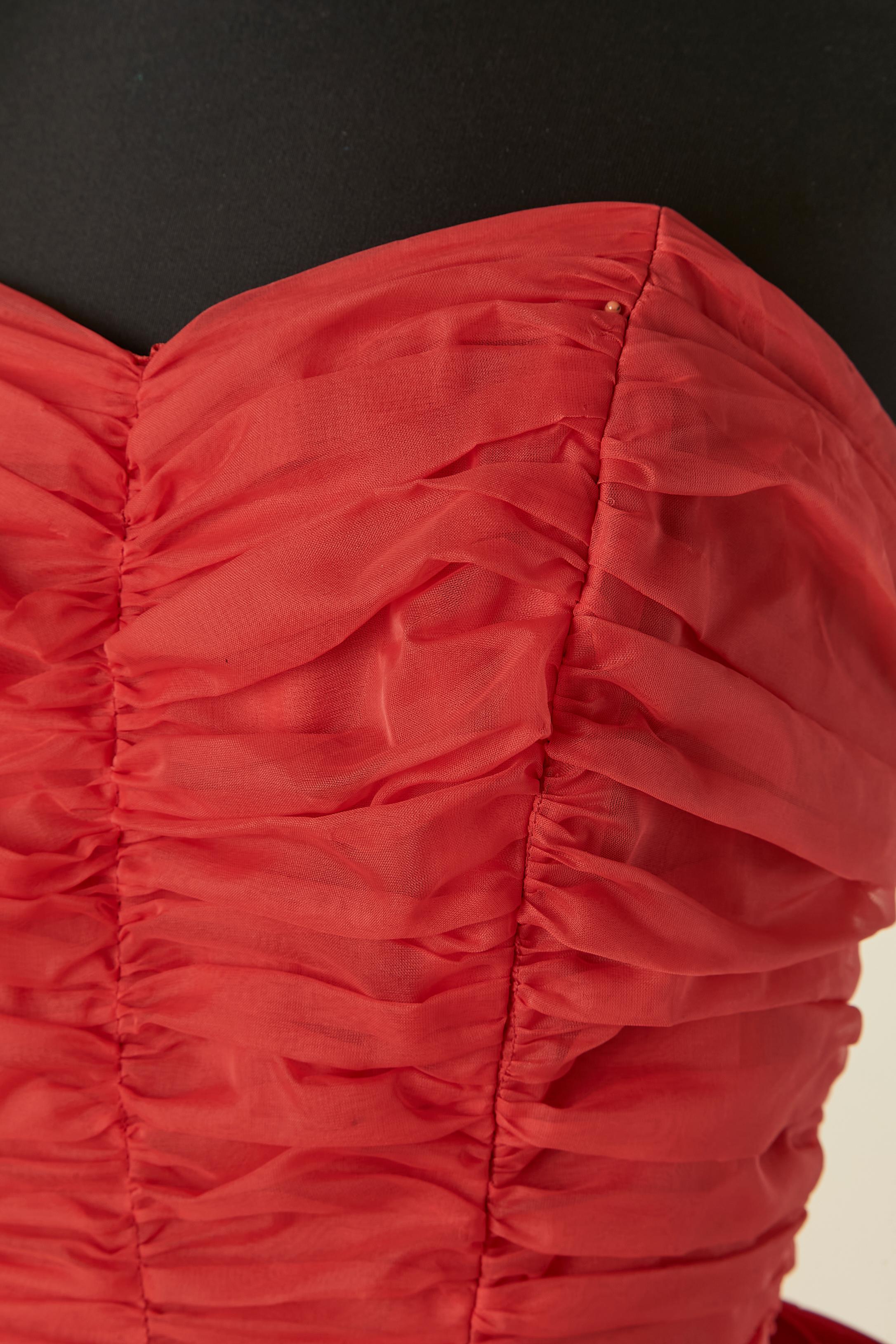 Robe de bal à bustier rouge. Il n'y a pas d'étiquette de composition du tissu, mais il s'agit probablement de polyester. Osseuse. Fermeture à glissière au milieu du dos. Arc sur le milieu du dos avec un snap en dessous. Jupon en tulle rigide. Pas de