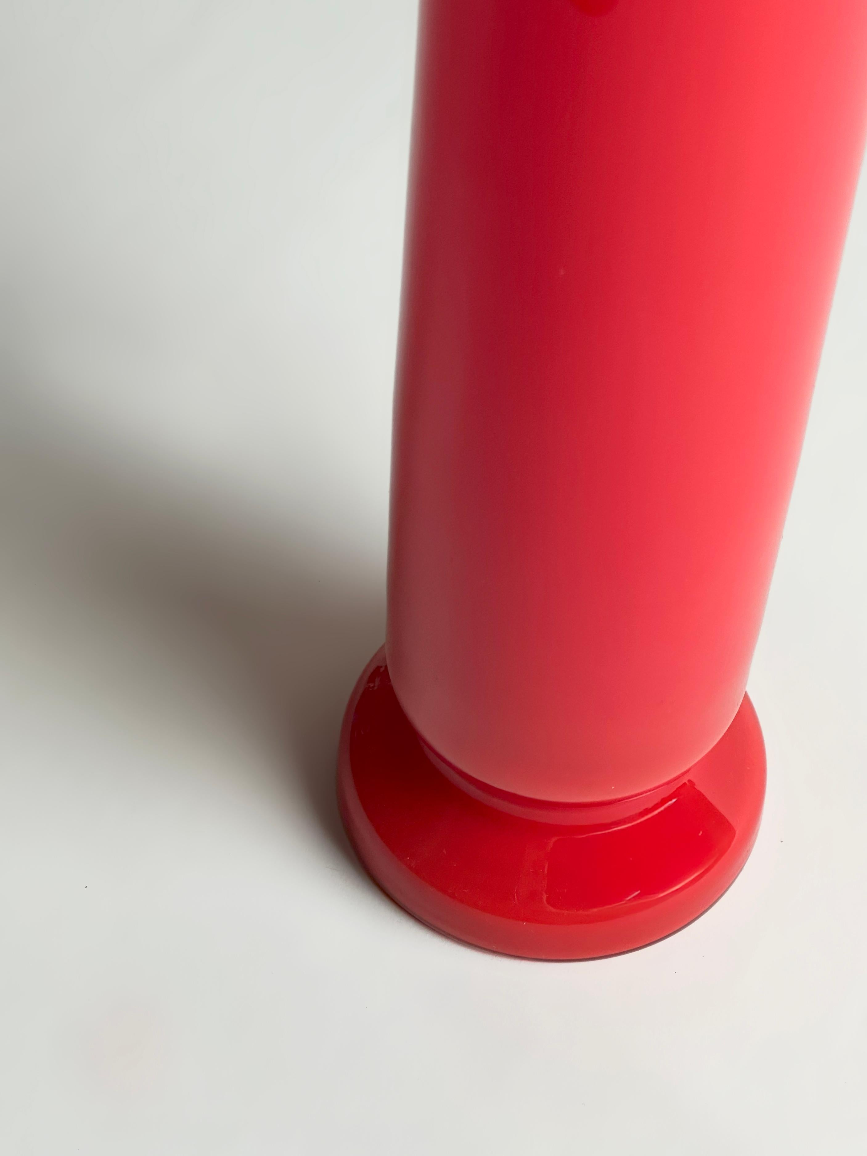 Jarrón columna de cristal rojo de Empoli, Italia, fabricado hacia la década de 1970.

El jarrón, fabricado en vidrio estucado, presenta una capa interior de vidrio blanco opaco recubierta de rojo brillante, que crea profundidad y una vívida
