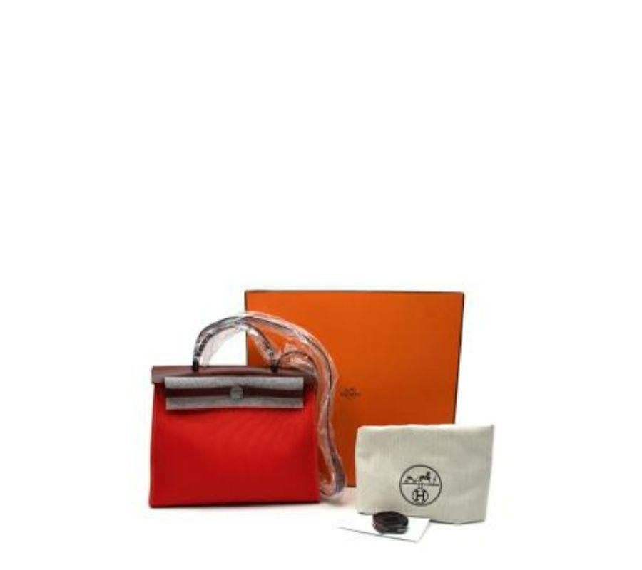 Hermes Red Herbag 
 
 It’s crafted from officier canvas and cowhide leather. The body (which is the biggest part) is built from canvas while the top part and the handle is made from real leather. 
 
 The front features the Clou de Selle closure,
