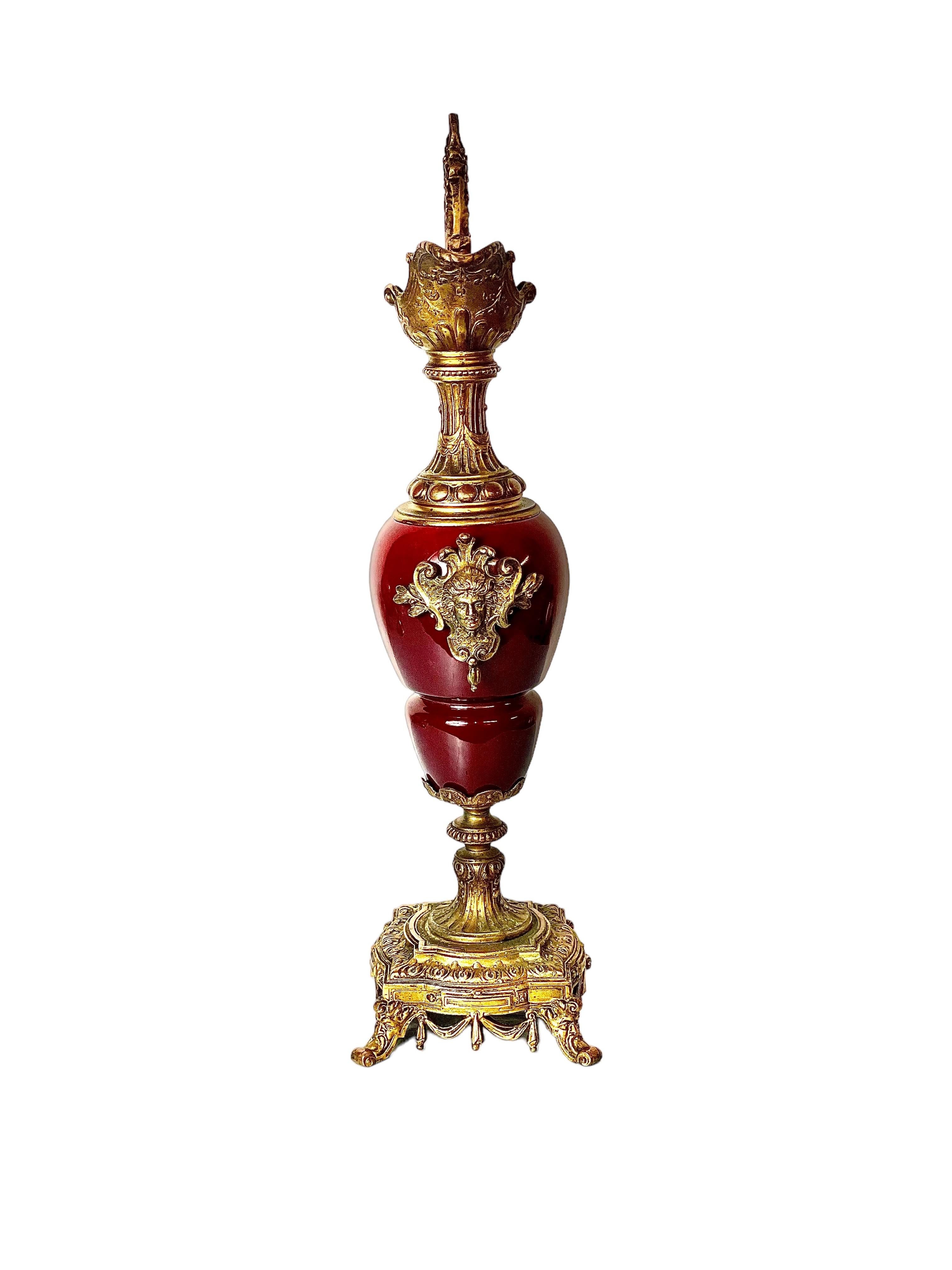 A very ornate French antique ewer urn with a gleaming, red ceramic jug body and gilt bronze foot and trimmings, dating from the beginning of the 20th century and modelled on the Renaissance style. This striking piece would originally have formed
