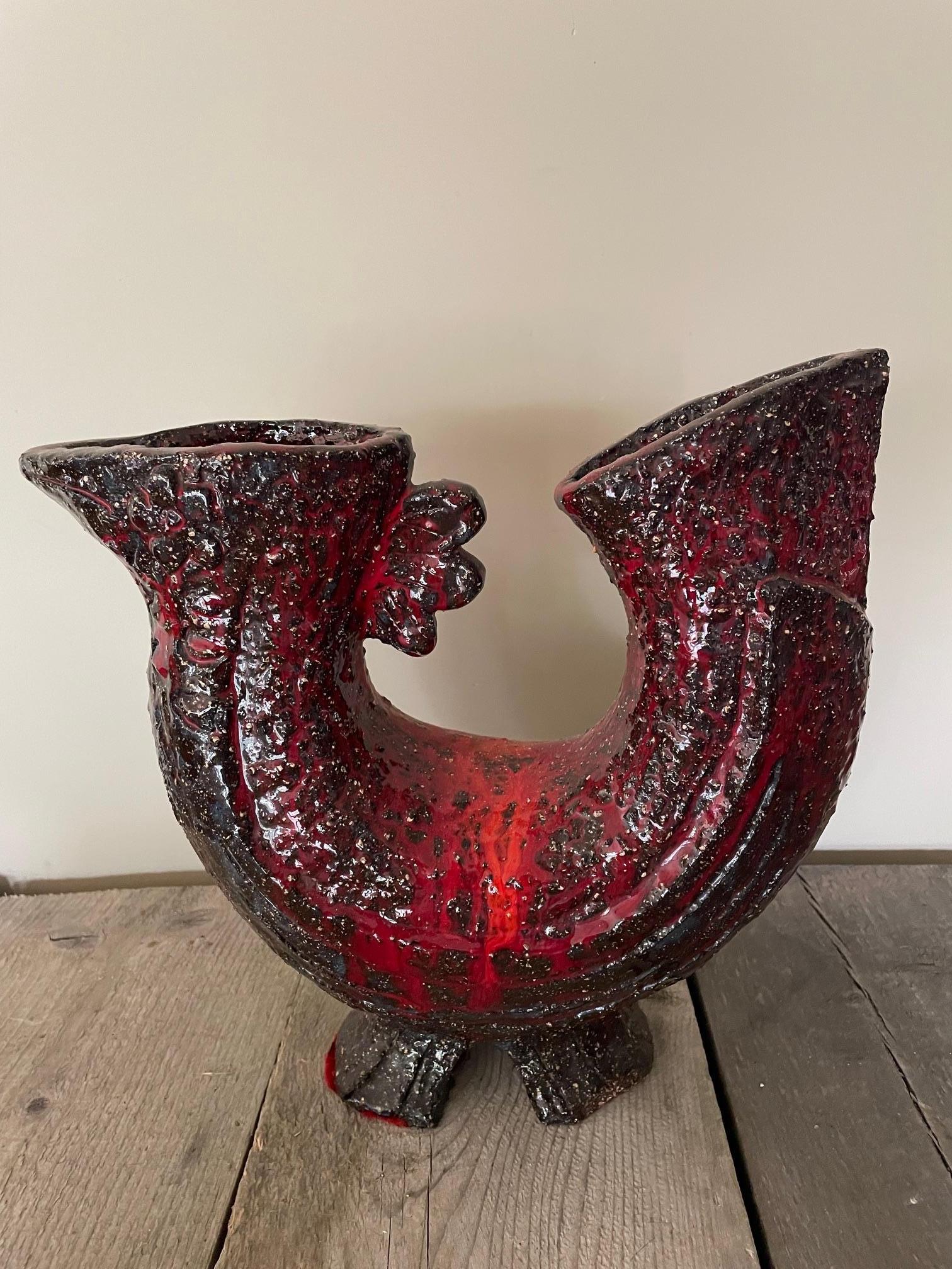 Un coq en céramique rouge de style Brutaliste très original en Fat Lava. Il peut être utilisé comme pièce décorative ou comme vase, car il possède deux extrémités ouvertes.
Cette pièce datant des années 1970 est très typique de l'époque où la