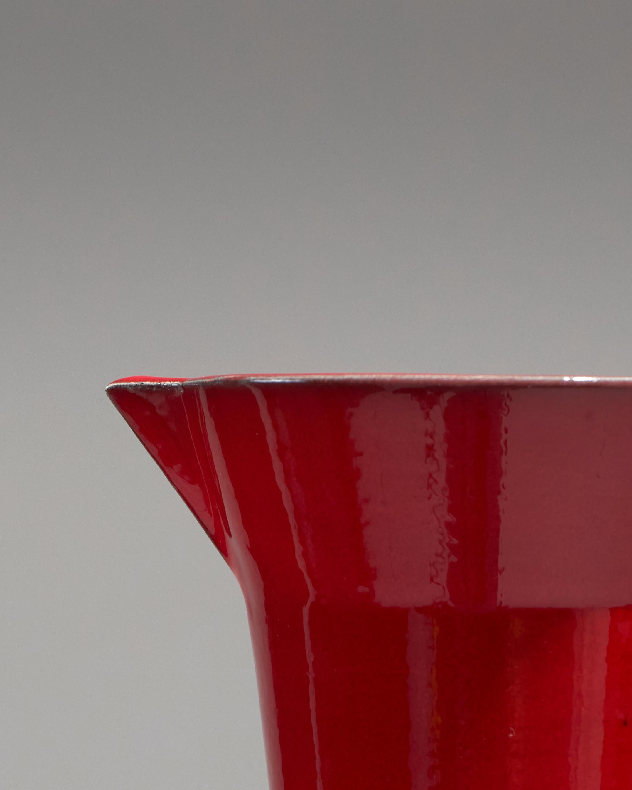 Pichet en céramique émaillée rouge par Olivier Gagnère, années 1990. Réalisation Atelier Picault à Vallauris. De forme élancée avec anse latérale, signature en creux M O G Vallauris. Très bon état, à noter une petite égrenure sur le rebord.