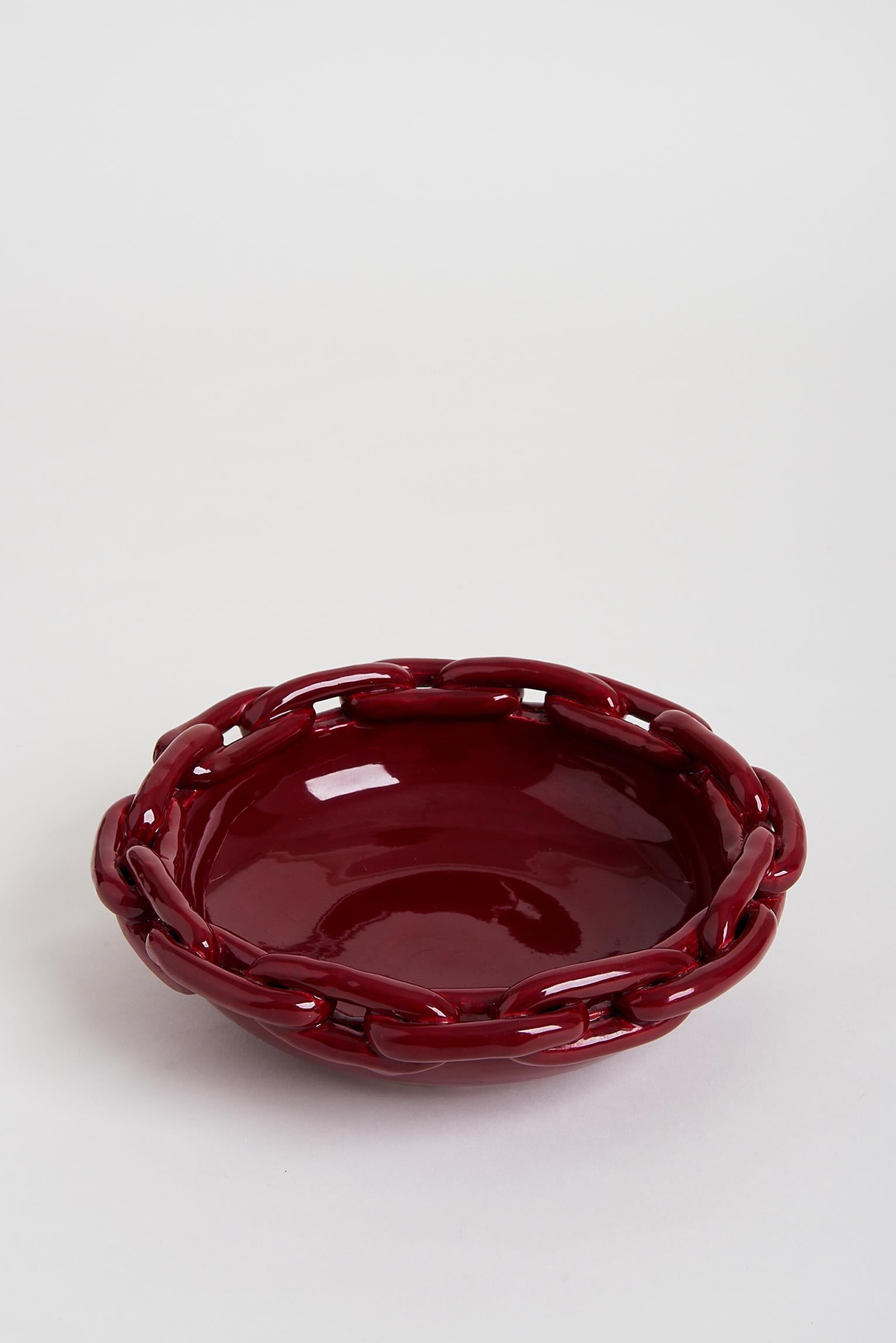 A large red glazed ceramic circular bowl, with a chain links border, attributed to Jerome Massier.
Stamped Vallauris,
France, circa 1950.
