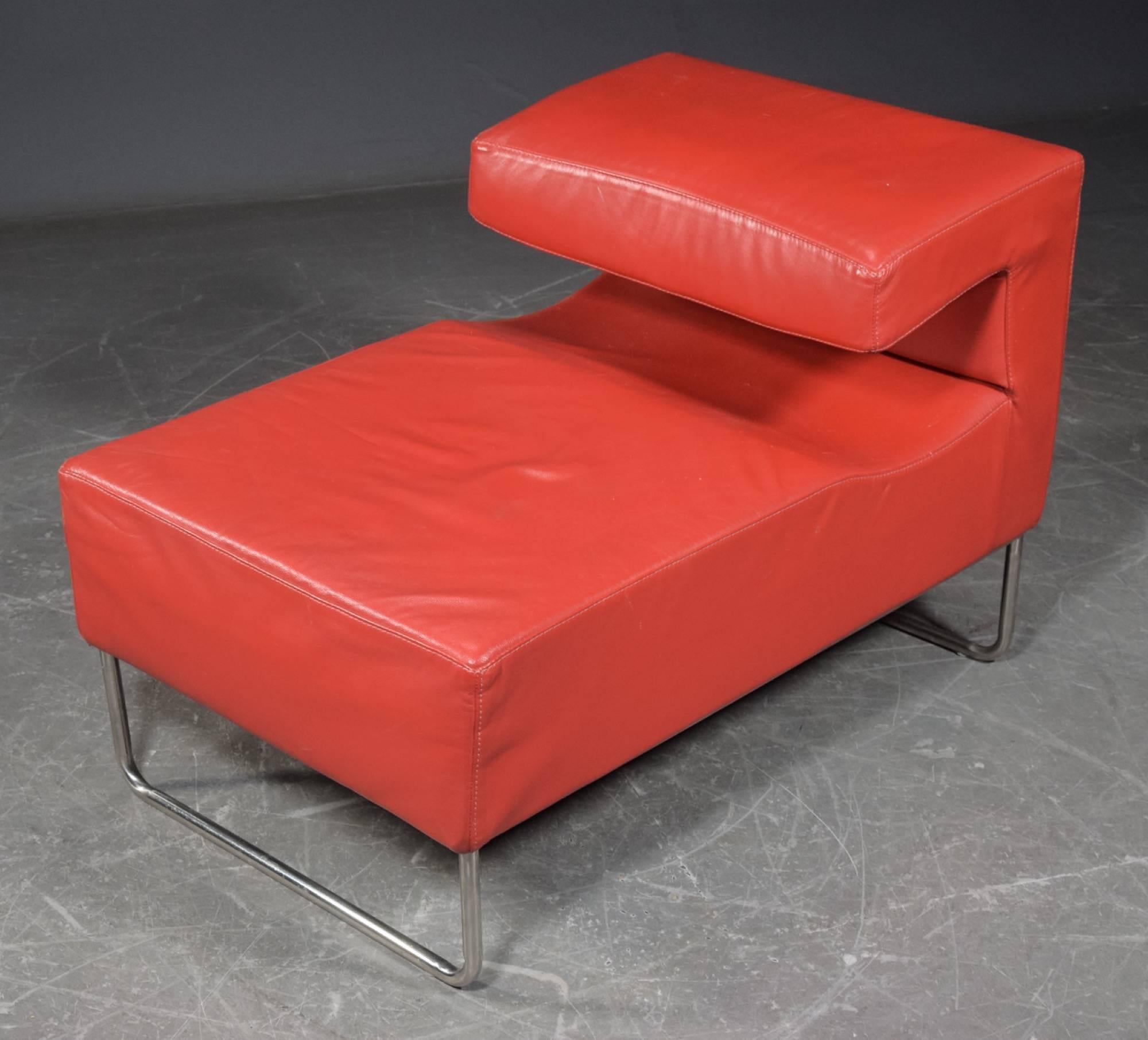 Chaise longue chair upholstered with red faux leather on a chromed steel frame.