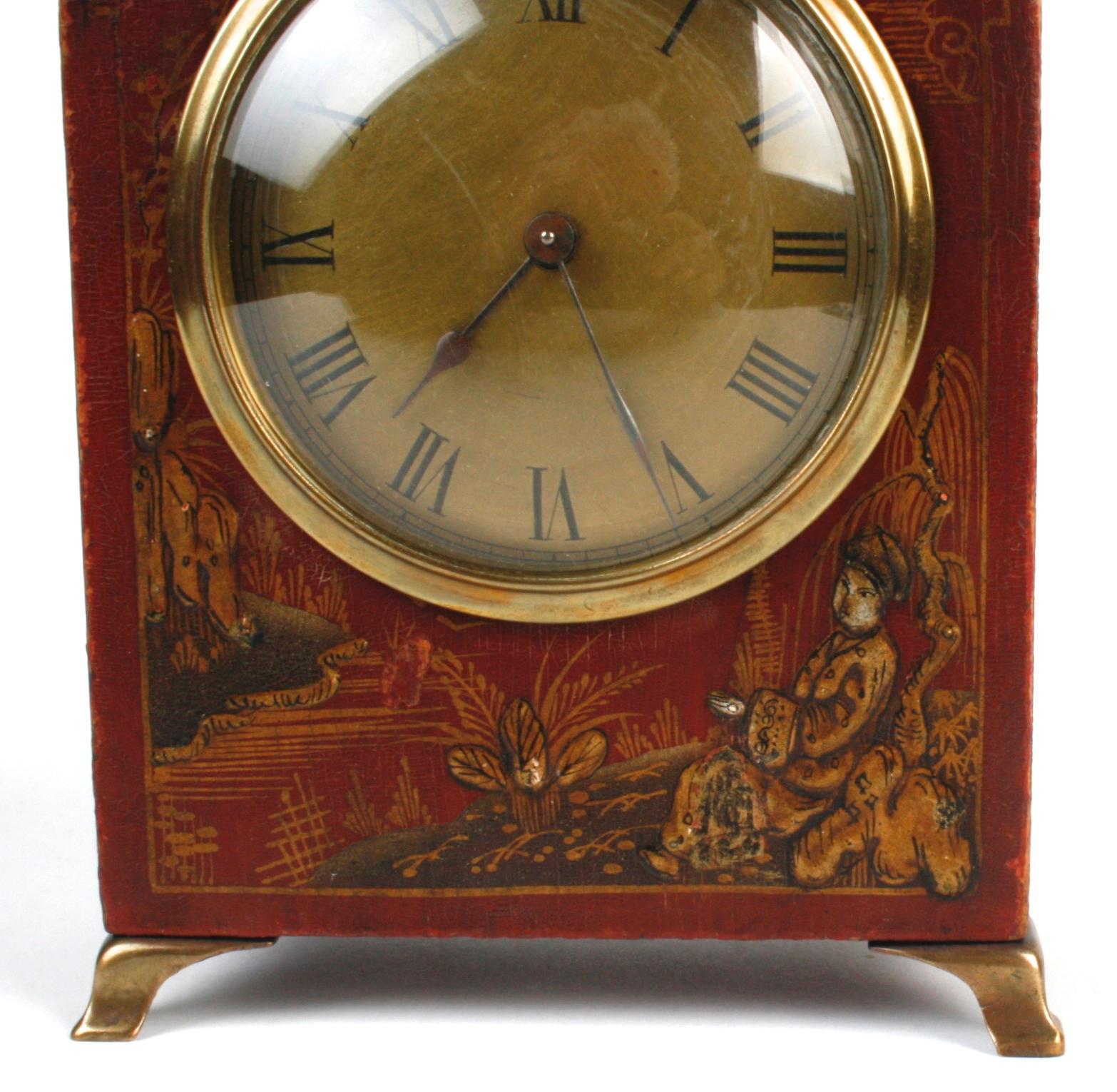 This beautiful clock containing French works is decorated with scenes of Asian country life. It has a decorative brass handle, finials, face and legs. The wooden case is painted red with raised details of gold and brown. A charming time