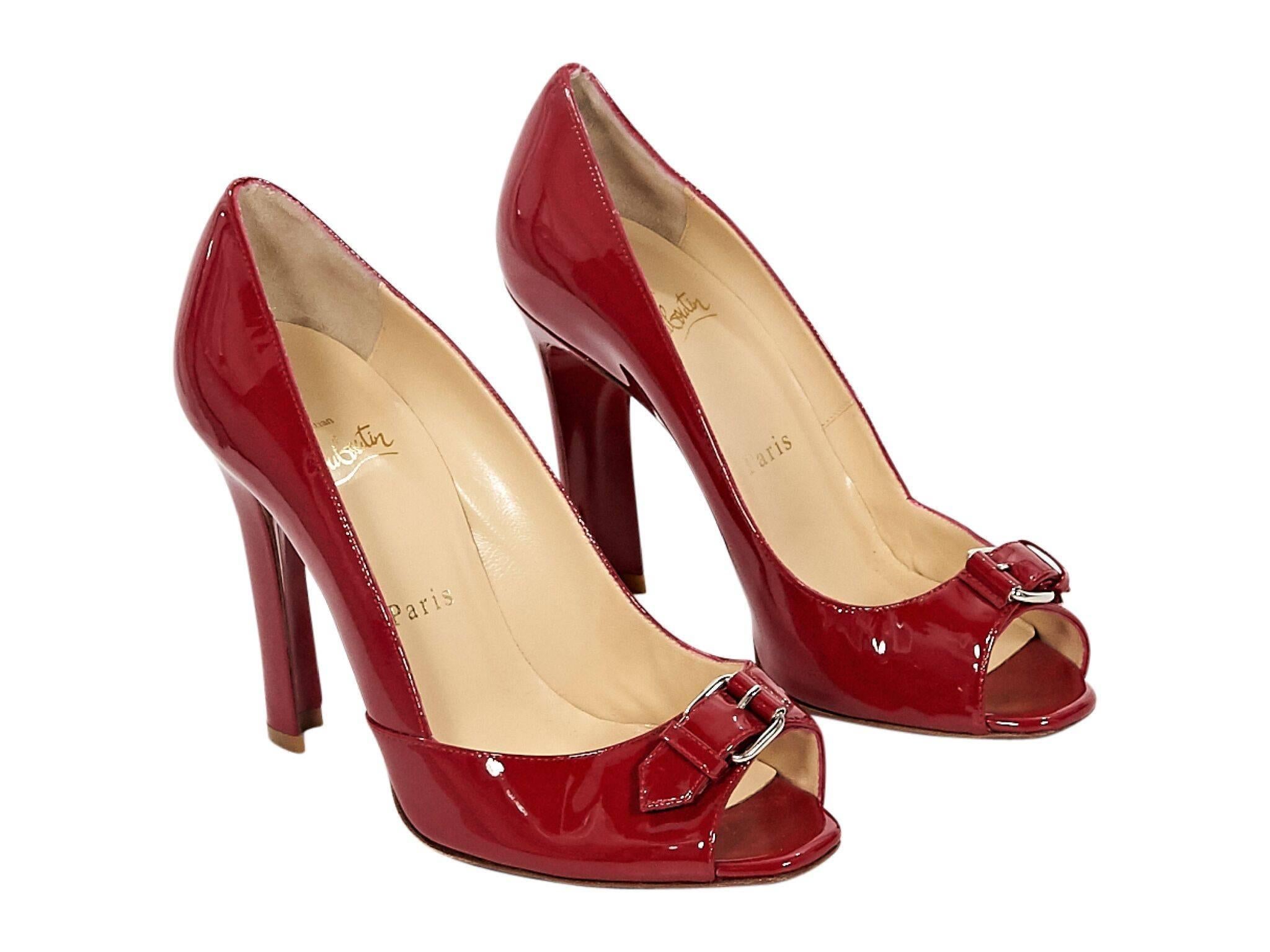 Product details:  Red patent leather pumps by Christian Louboutin.  Buckle detail accents vamp.  Peep toe.  Iconic red sole.  Slip-on style.
Condition: Pre-owned. Very good. 
Est. Retail $835
