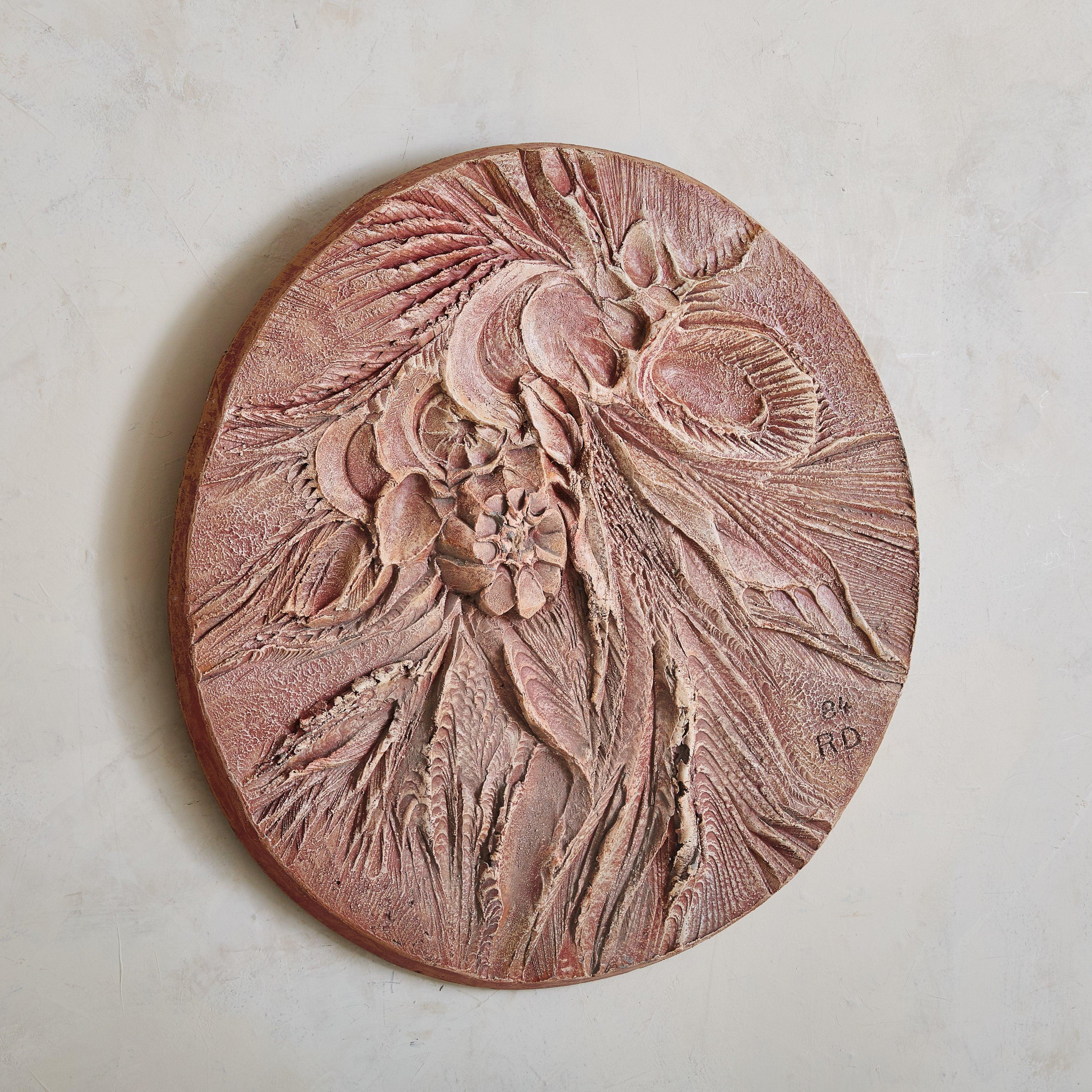 A large circular wall sculpture by French artist Roger Desserprit. This bas-relief is made out of concrete, with a cement plaster surface finished in a soft rose hue. Abstract floral motifs and intricate texture make it interesting from every angle.