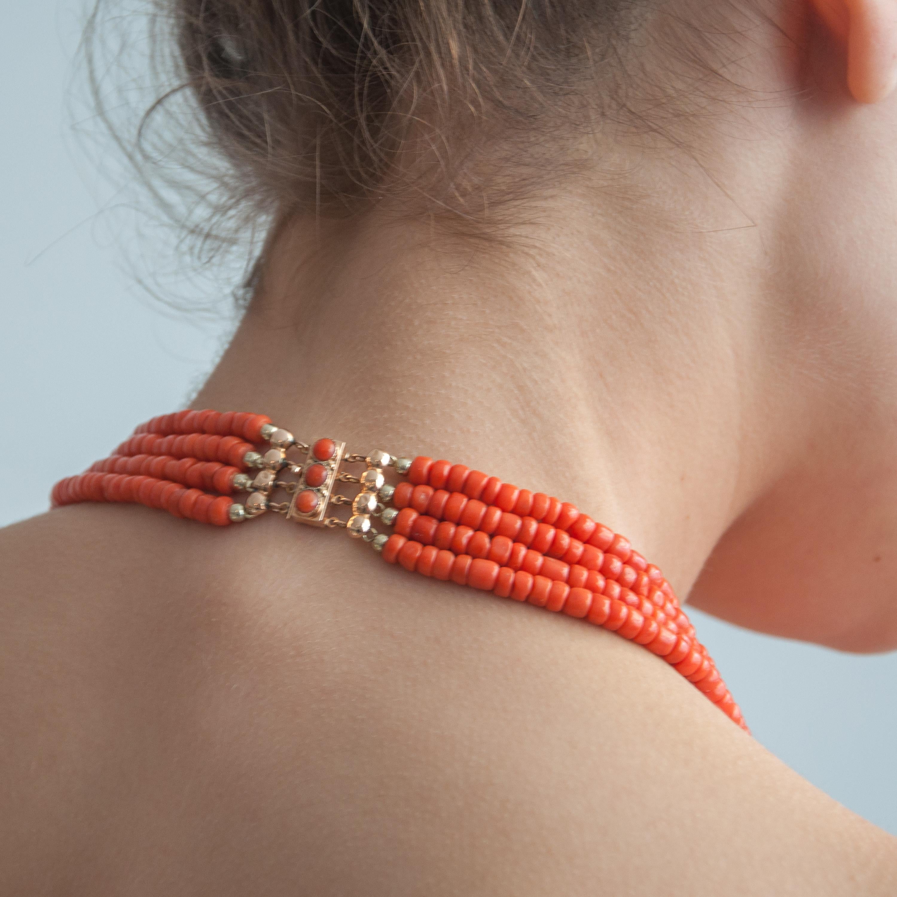 This mid-century coral beaded necklace is created with a 14 karat gold clasp. The necklace is made with a beautiful rectangular shaped clasp set with three round-shaped coral cabochon stones. The four strands are created of natural coral set with