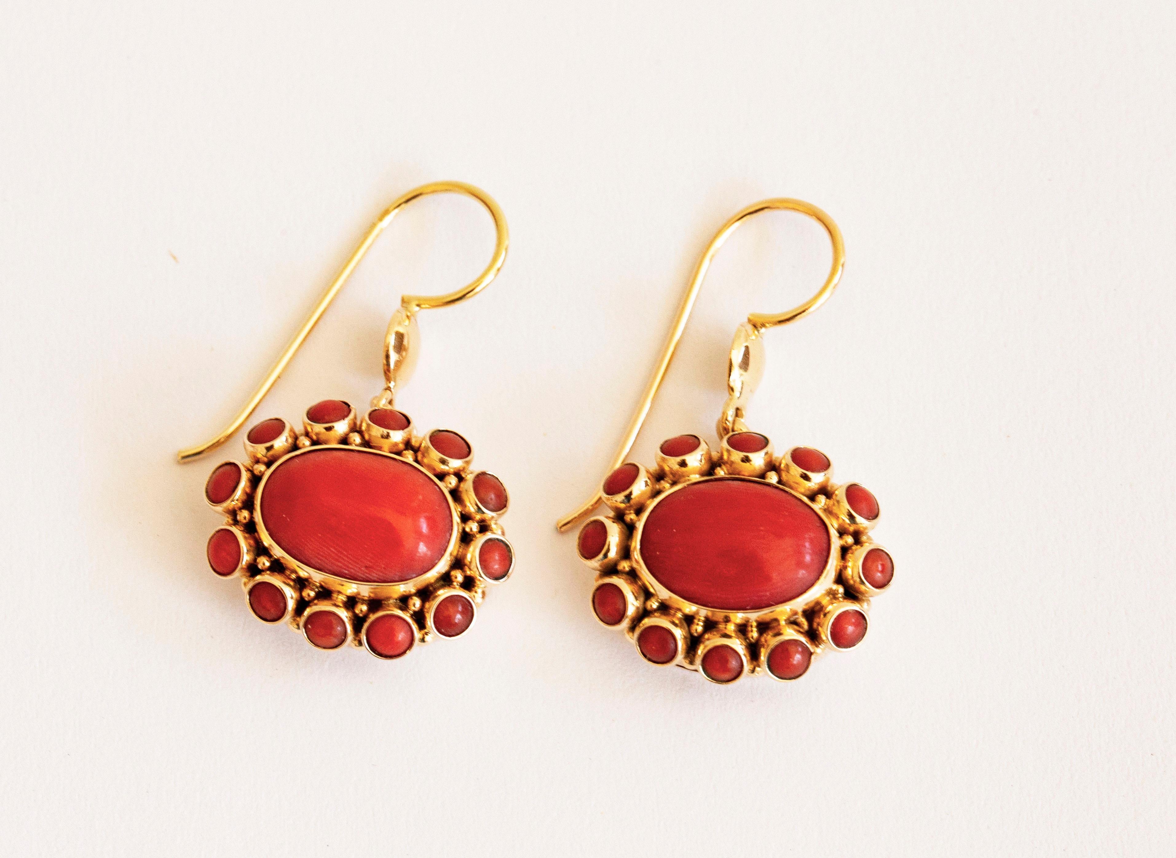A pair of vintage Dutch pendant earrings made of 14 karat solid gold and an entourage of red coral. The coral beads feature a nice red color and the earrings are in really good condition with lovely age related patina. 
The earrings are 38 mm long
