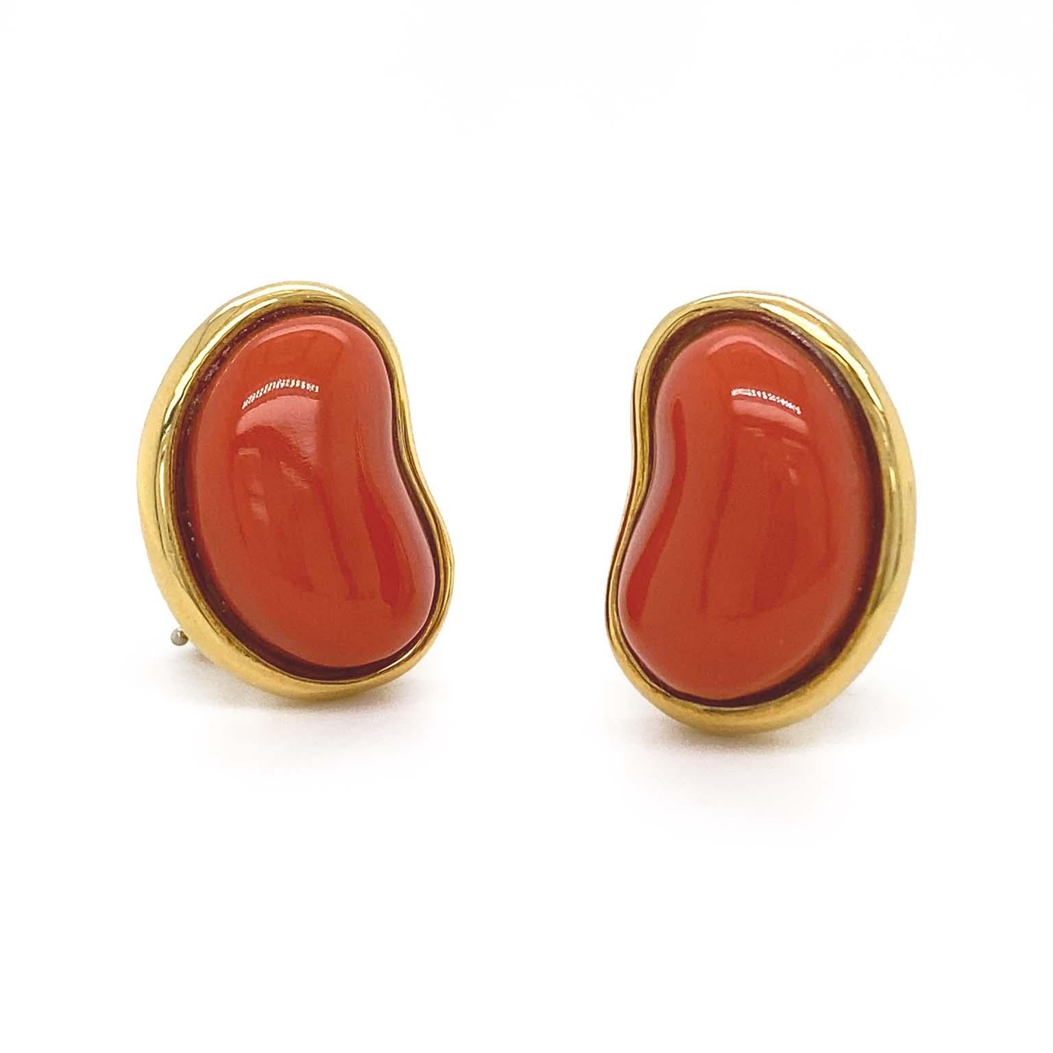 The blazing hue of polished red coral is the luminary of these earrings. The gem is carved into a bean shaped cabochon with its curve turned inward. Set in 18k yellow gold, the metal brings both accent and light. The total weight is 3.8 carats of