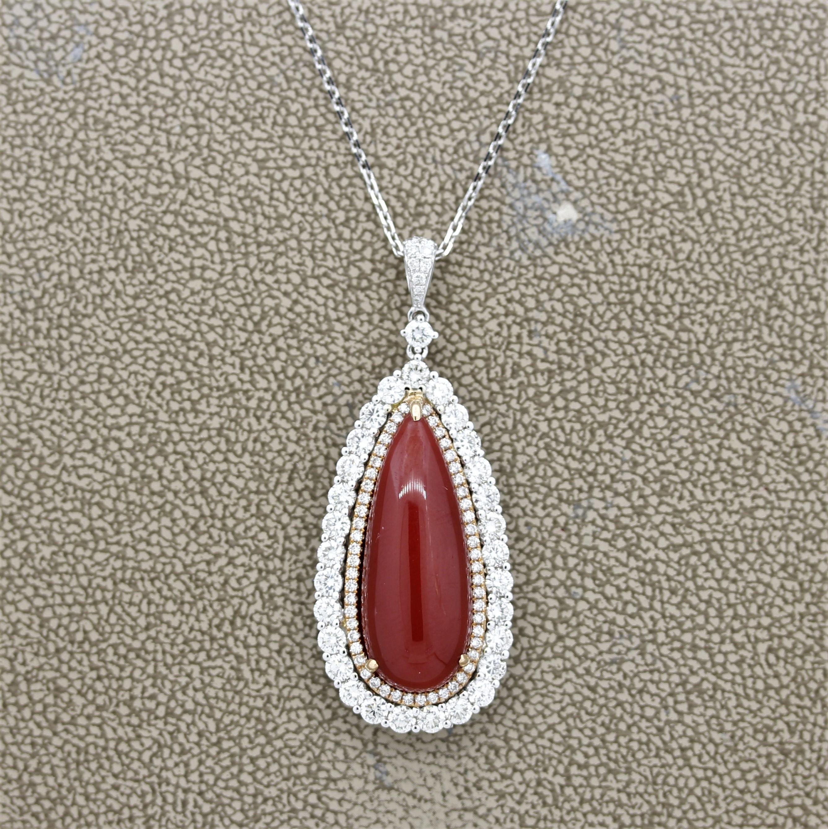 An extra fine piece of natural red coral polished as a smooth drop shape. It weighs 14.70 carats and most likely from the Mediterranean due to its amazing red color. Accented and haloing the coral are 2.29 carats of round brilliant cut diamonds. The