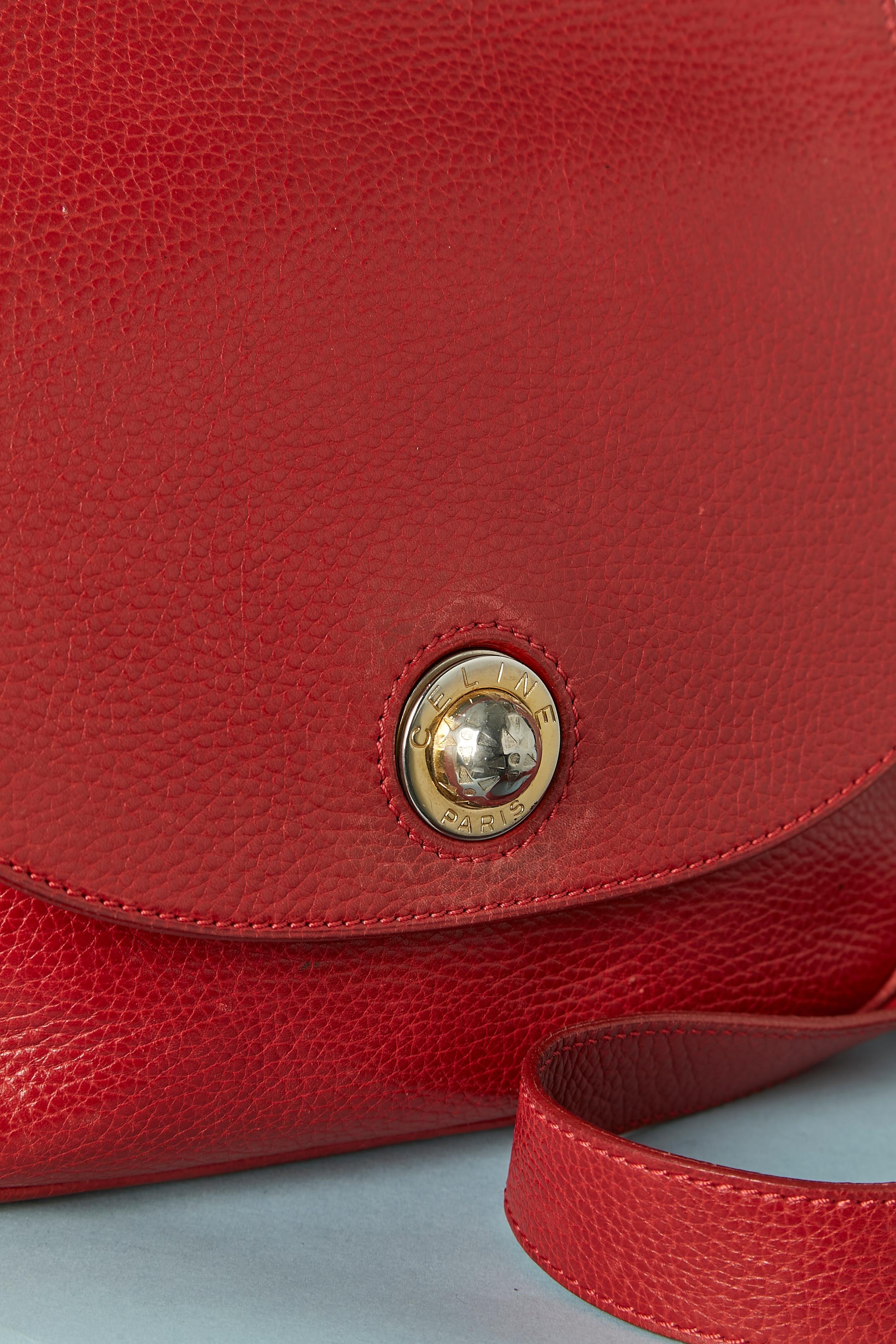 Bolso cruzado rojo de piel granulada con cierre de brande en la parte delantera central. Forro de cuero rojo. 
Un bolsillo interior con cierre de cremallera y forro de tela. Bandolera ajustable. 
TAMAÑO : 24cm X 20cm X 8cm
Longitud de la correa: 115