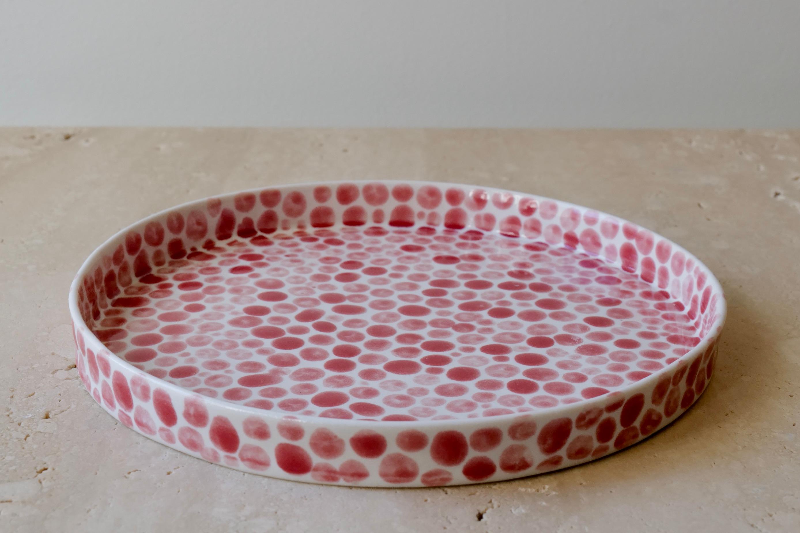 Ceramic plate perfect for serving or part of a set. Hand-cast in porcelain and once bisque fired, each dot is hand-painted with a red glaze. An unconventional layered glazing technique, developed by the artist, is used in these cast porcelain