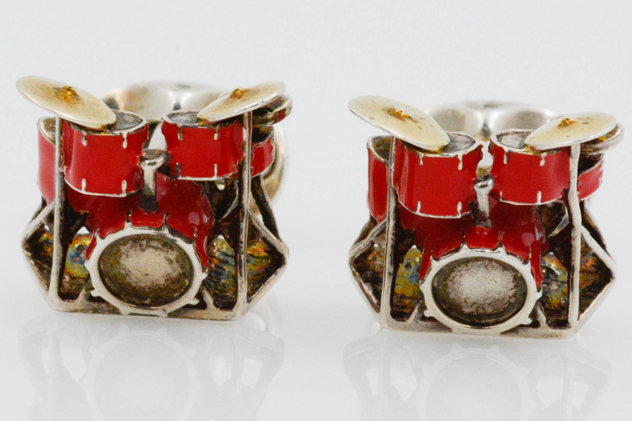 These poppy red enamel sterling silver drum set cufflinks are perfect for any drummer. These cufflinks feature a full drumset with cymbals. They have dome oval spring links. 
